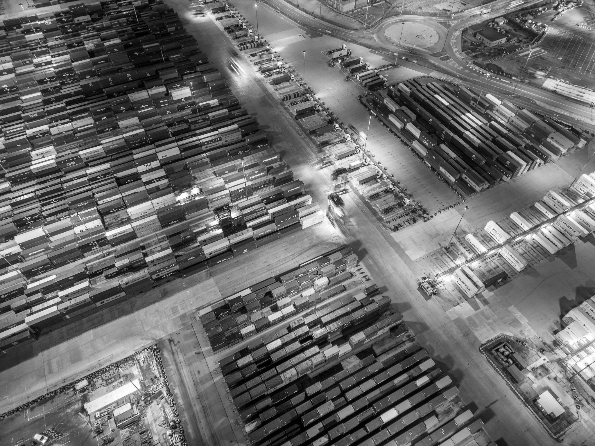 Aerial view of a bustling shipping yard with rows of containers, showcasing global trade and logistics at scale.
