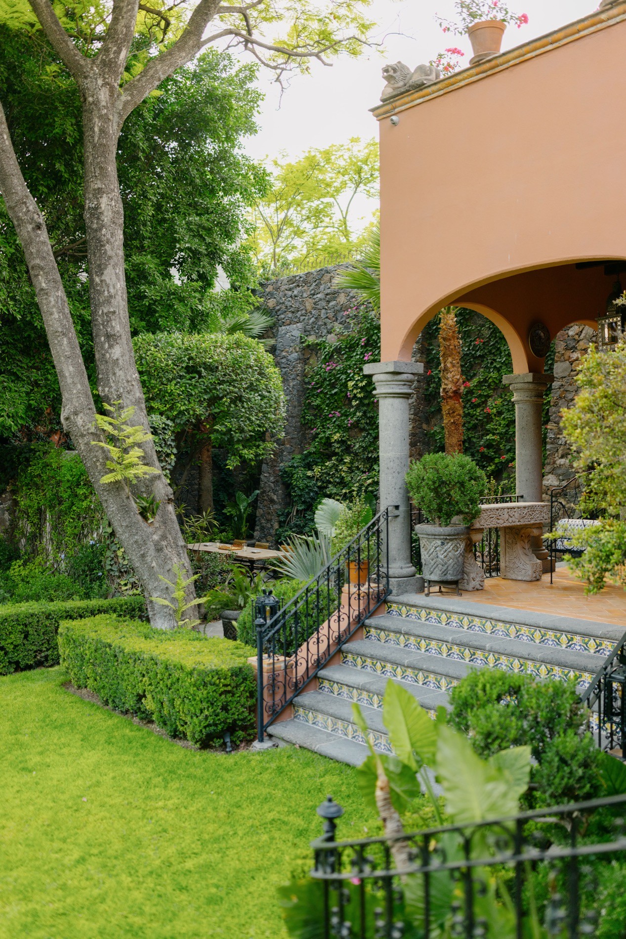 La Residencia San Miguel garden with stone steps, arched entrance, and rooftop terrace planters