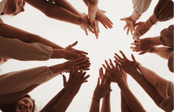 A diverse group of people raising their hands together in a supportive and empowering gesture.