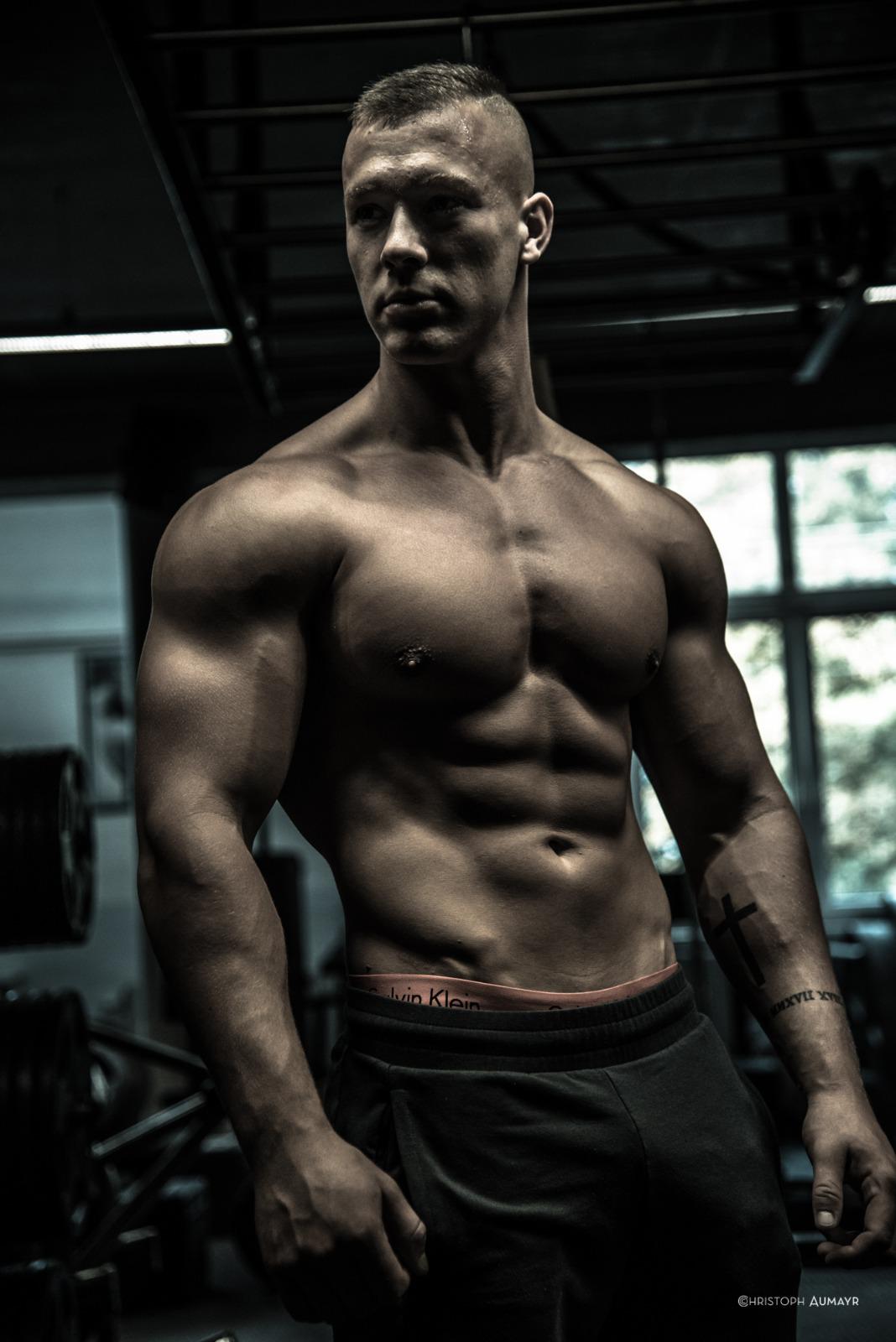 Two individuals are working out in a gym, focusing on dumbbells and strength training equipment.