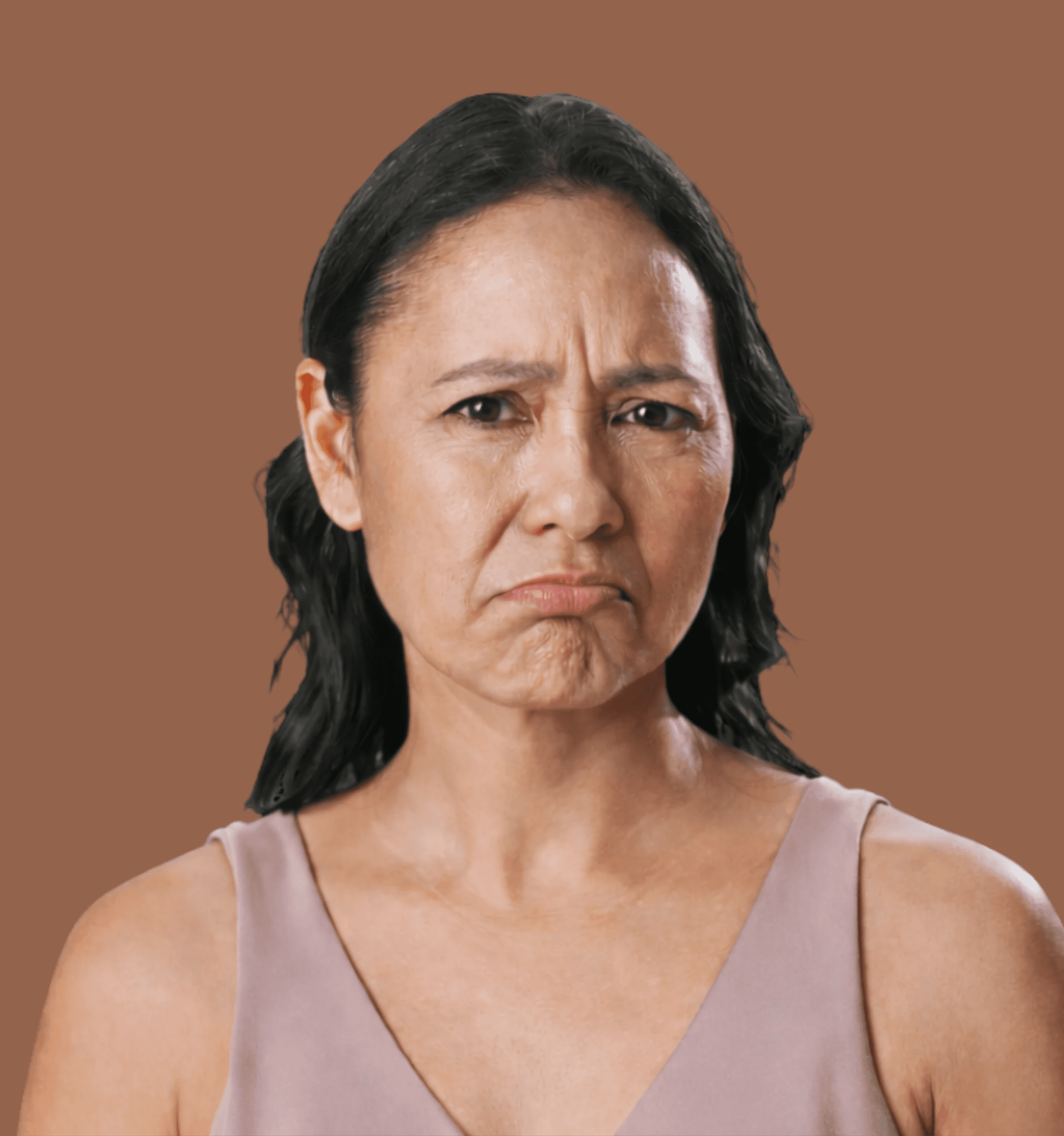 Smiling female therapist with short gray hair, wearing a brown top and a purple shawl, surrounded by a cozy background.