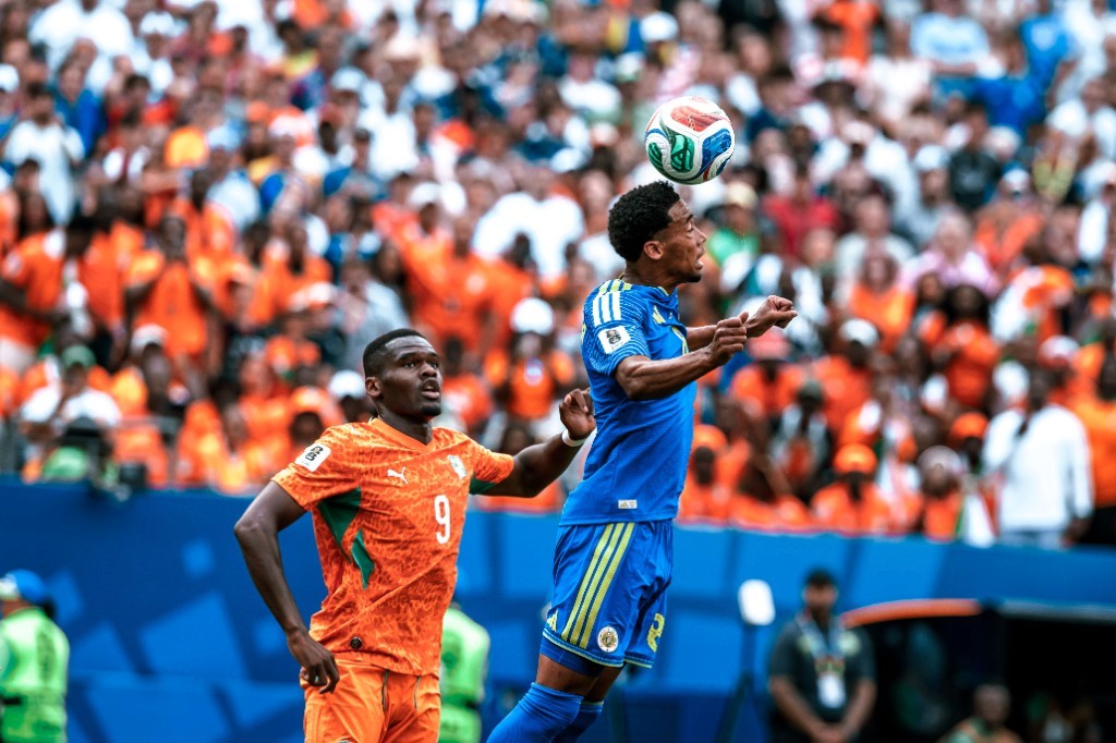 Curaçao and Ivory Coast players battle for a high ball as orange-clad fans fill the Philadelphia stands