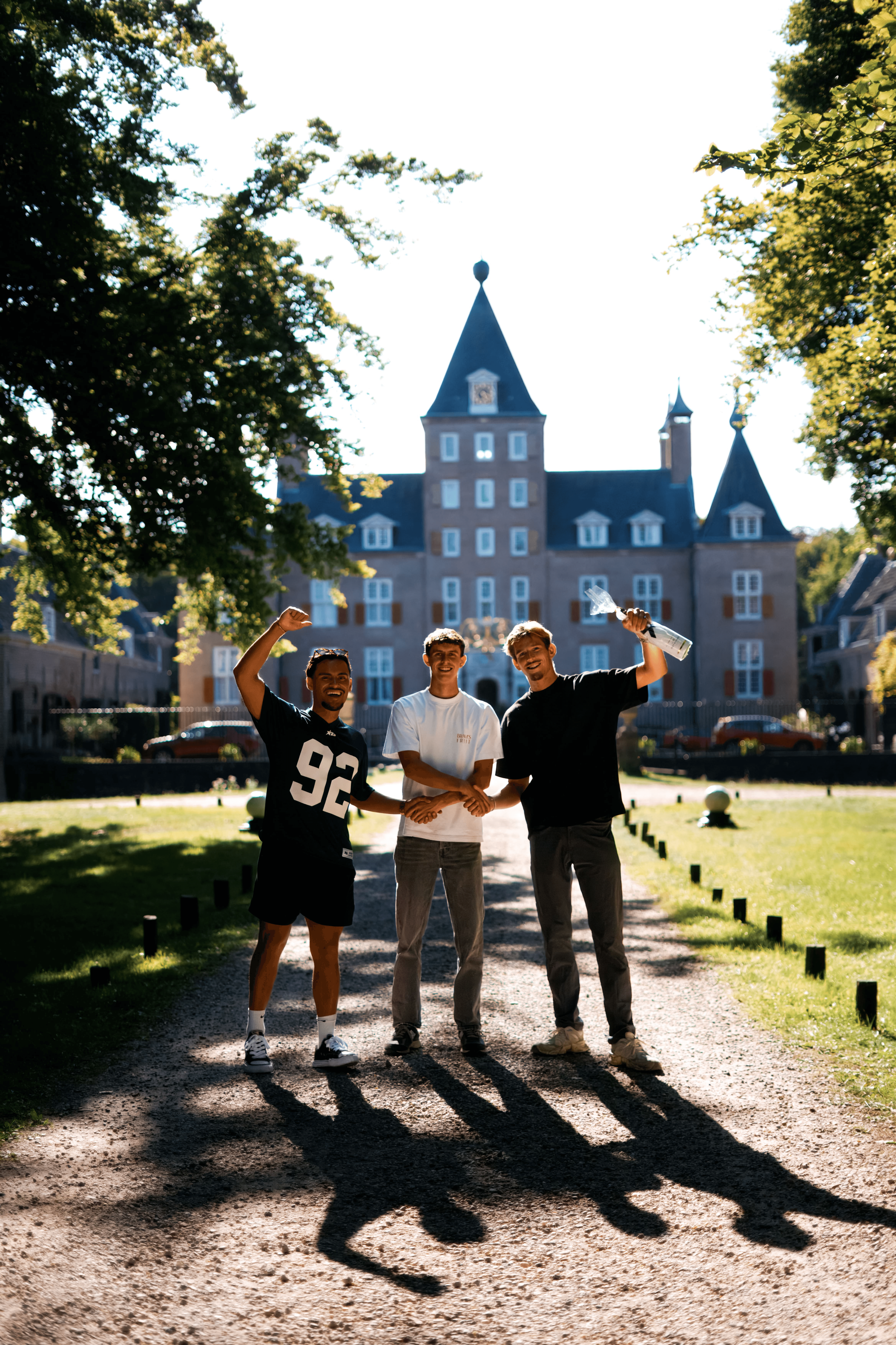 Drie vrienden juichen op een oprijlaan voor een kasteel