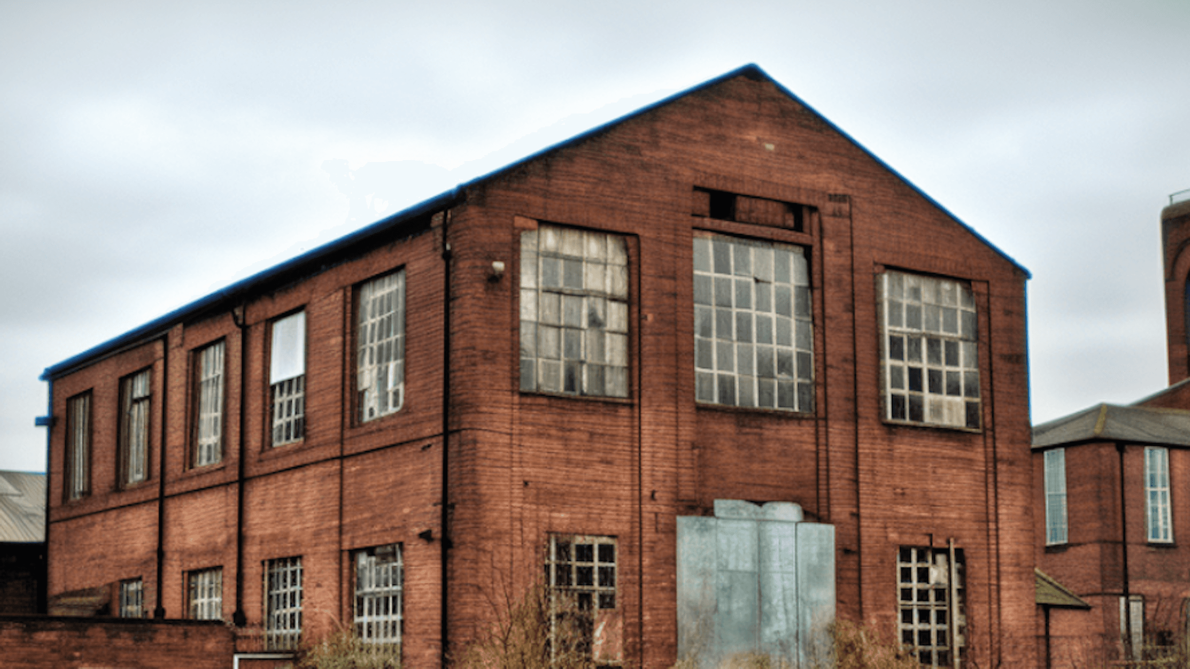 Brick building with large windows, featuring a symmetrical design under a cloudy sky.