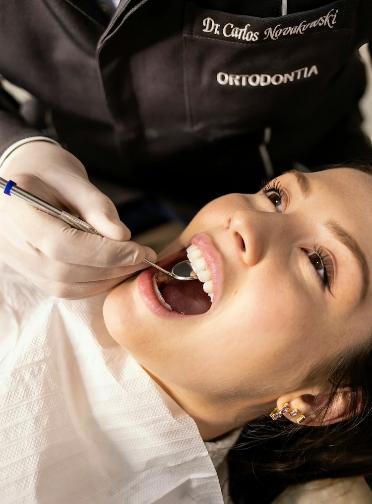 a girl lies in the dentist's chair and the doctor looks for cavities with a mirror
