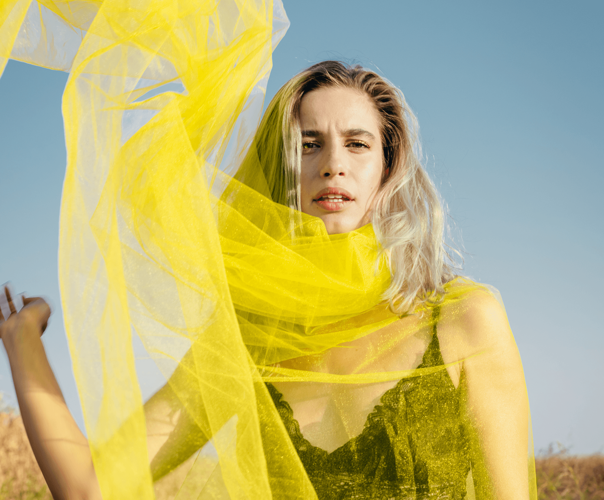 Woman in yellow fabric against blue sky