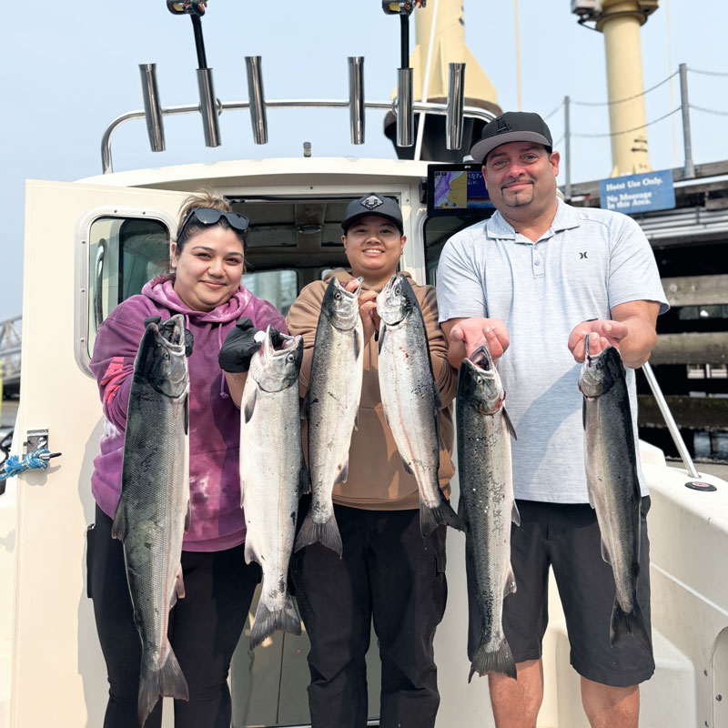 Three people each holding a salmon