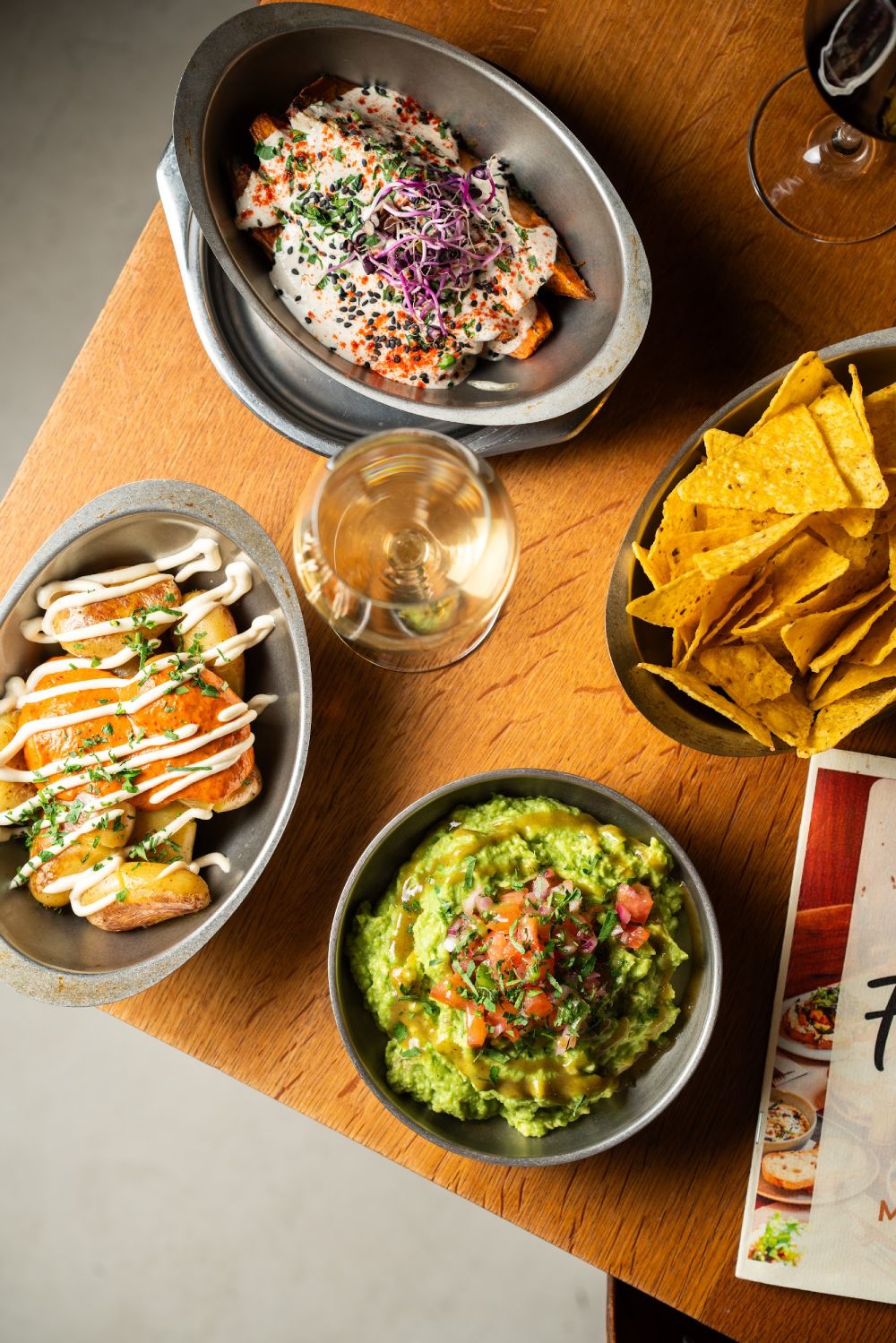 Vegetarian tapas from above — guacamole with nachos, patatas bravas and sweet potato with natural wine at Faire. Tapas & Wine, Eixample Barcelona