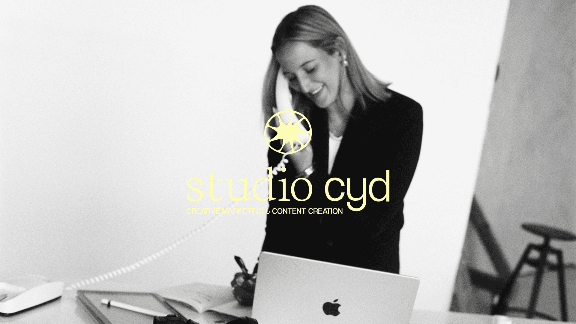 A thoughtful young person with dark hair gazes to the side, captured in soft black and white lighting.