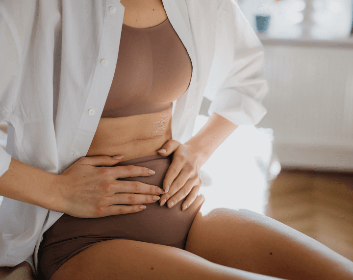 Woman holding her lower abdomen, representing female pelvic health concerns