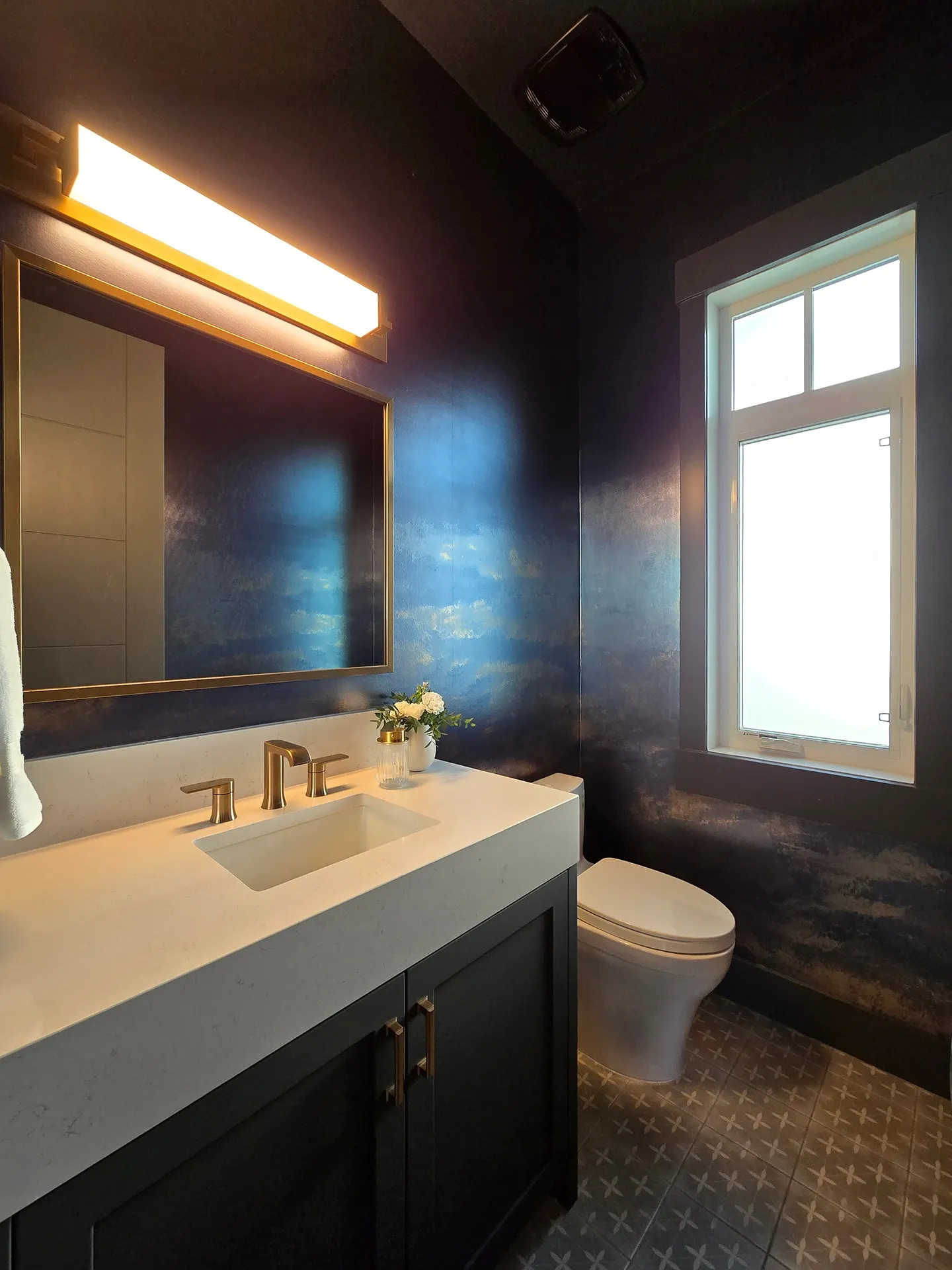 Dark, moody powder room with dark wallpaper, vanity, and lighting.