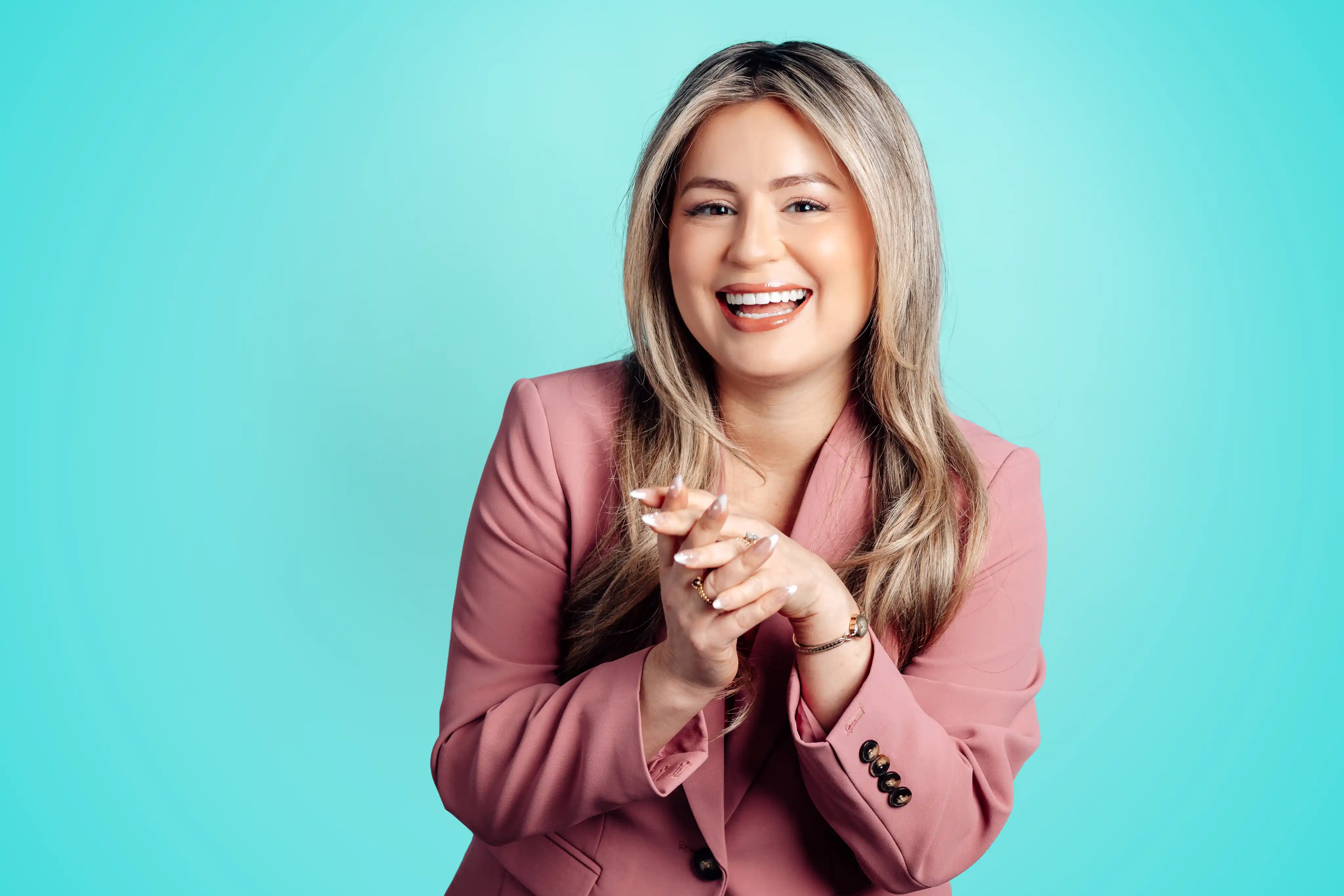 Playful personality portrait against teal backdrop wearing pink blazer for a Tampa branding photographer client