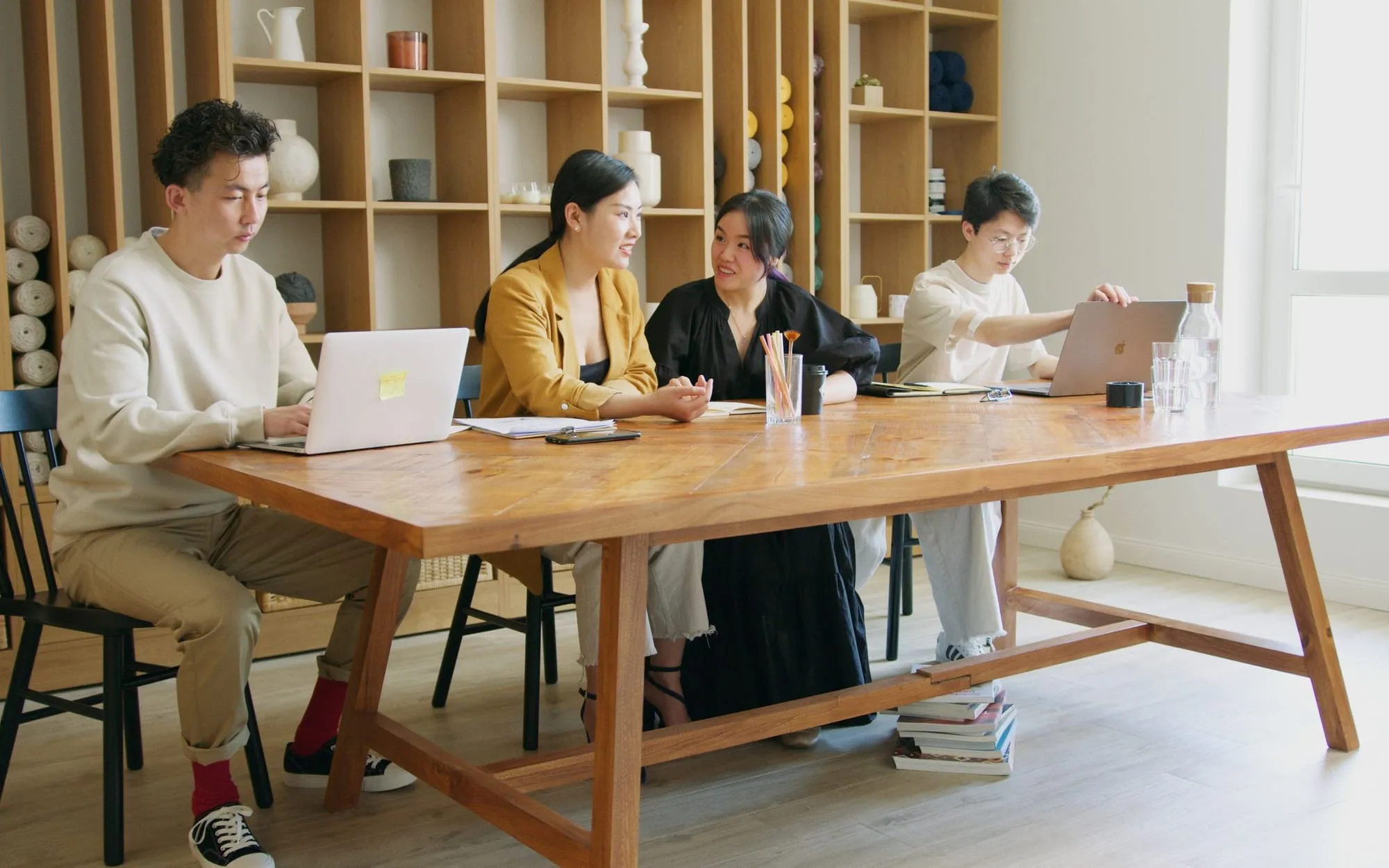 A team gathered around a table of laptops, discussing their work