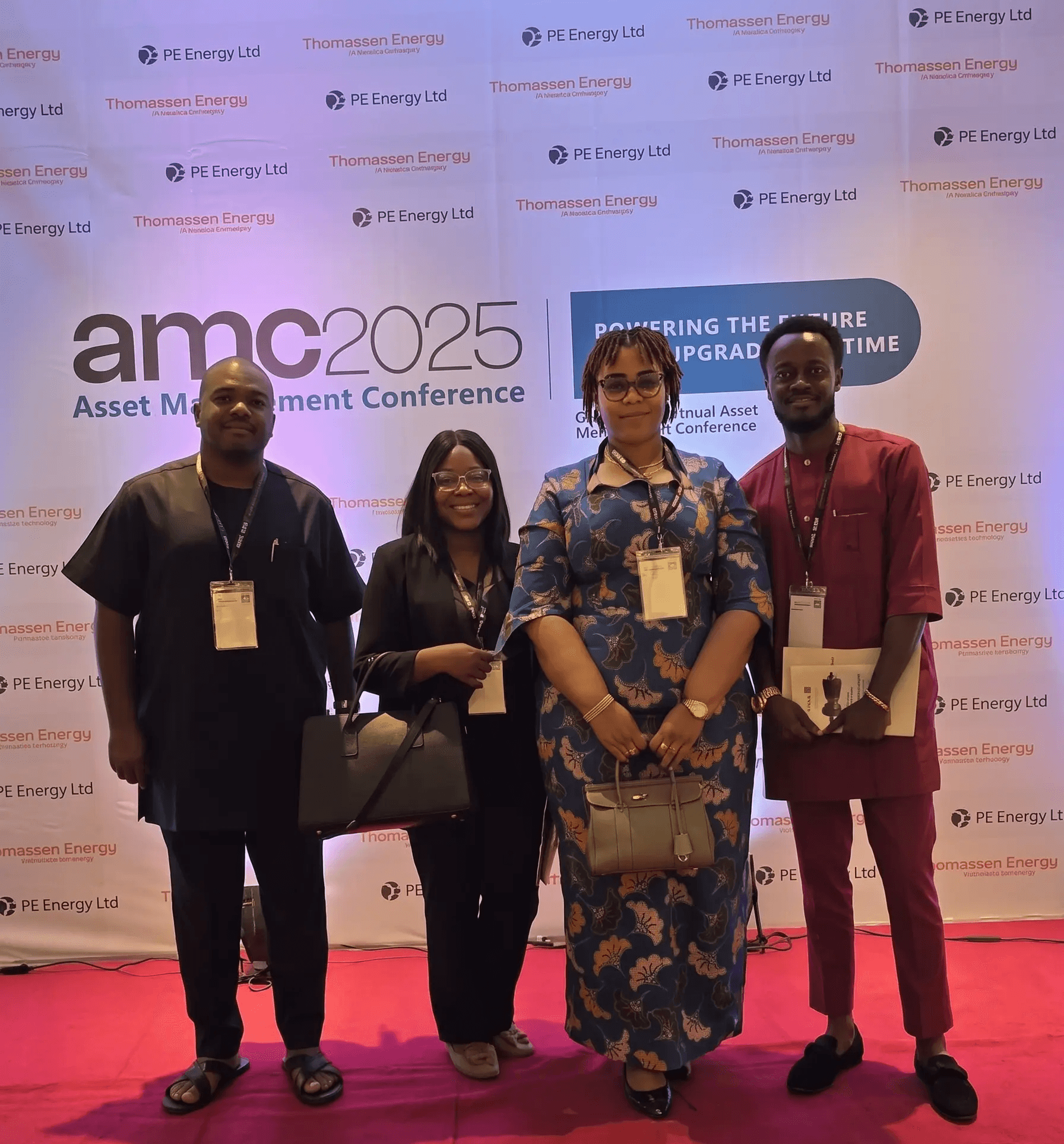 Four attendees at the 2025 Asset Management Conference, standing in front of the event backdrop.