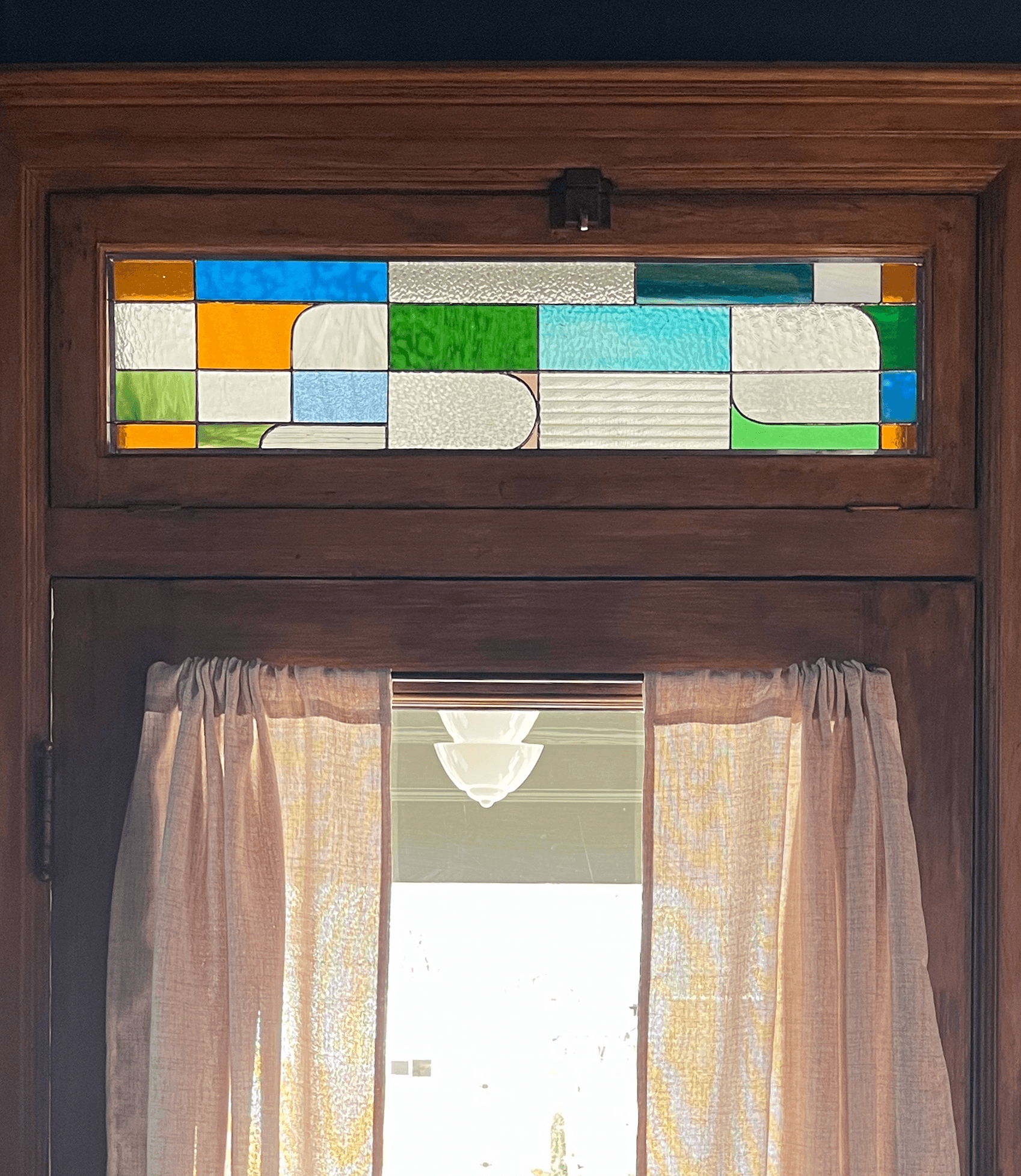 Small horizontal stained-glass transom with clear textured panels and jewel-toned accents