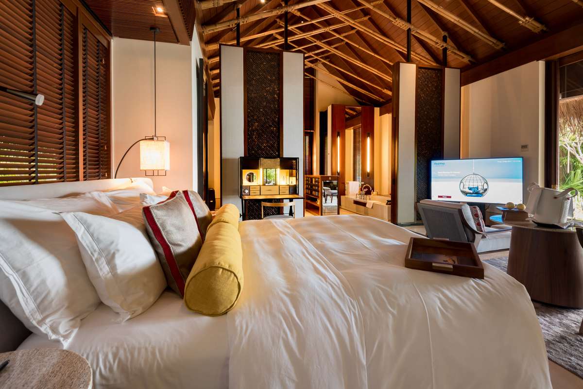 A luxury bedroom with two large beds featuring white linens and decorative pillows under a rustic wooden beam ceiling.