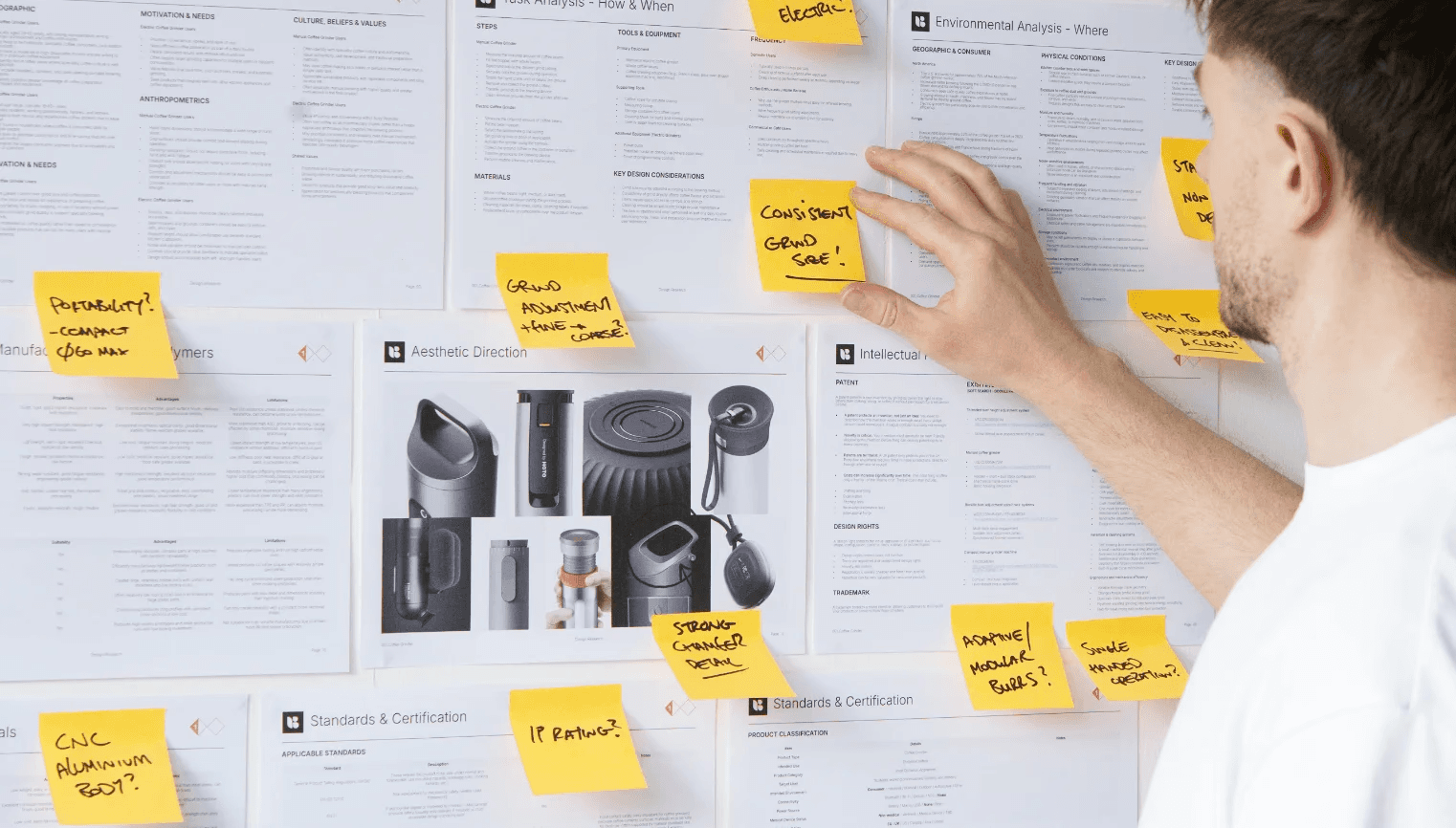 Industrial designer presenting and interacting with a design research board during a product development workshop.