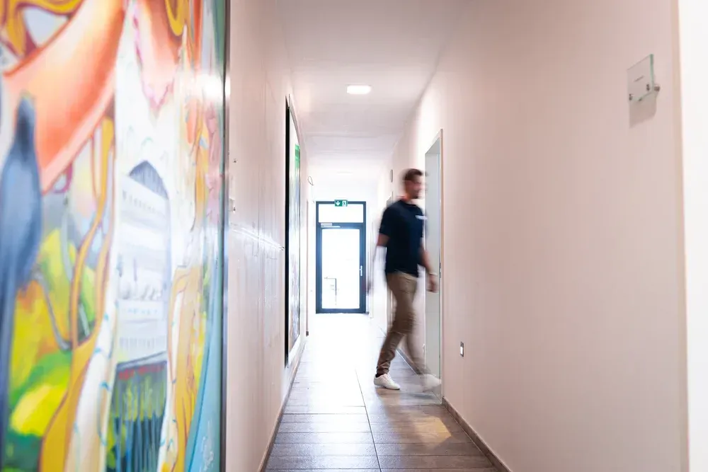 Mann im Gang, geht auf Tür zu, bunte Wandbemalung