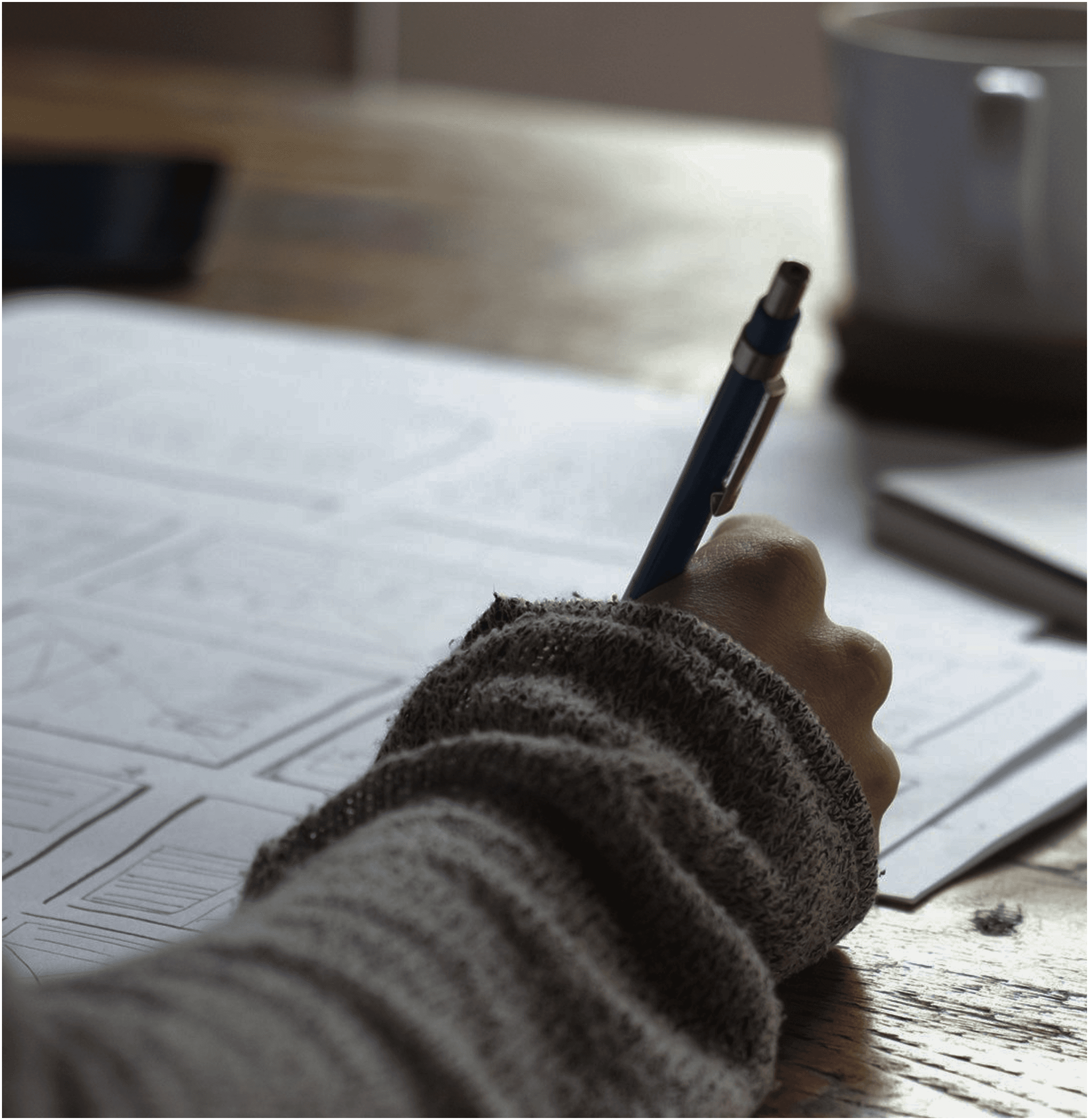 Sketching or writing with a pen on paper.