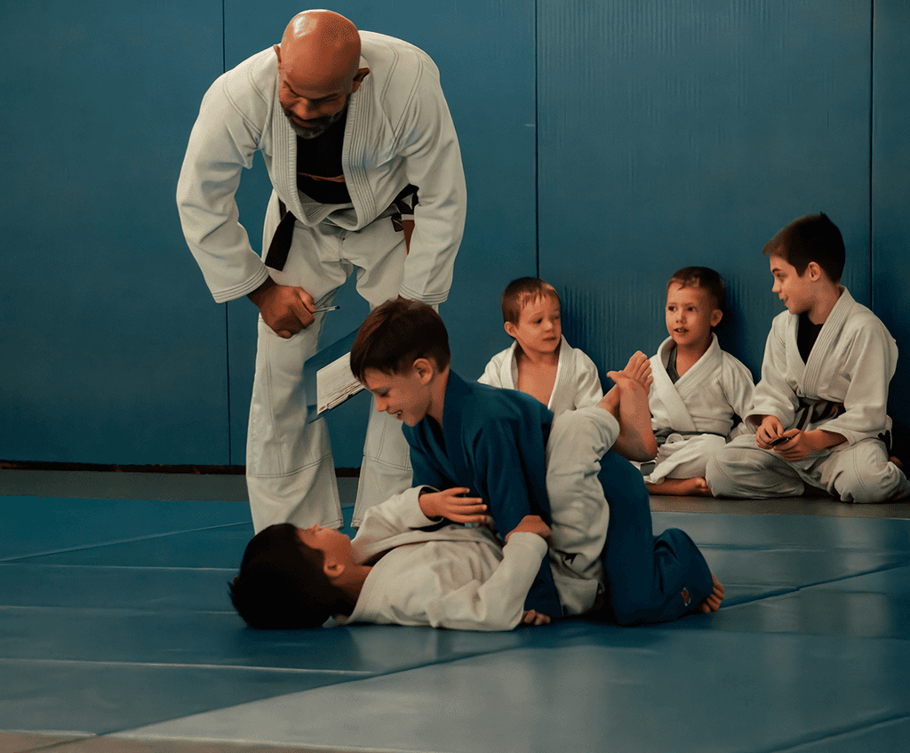 Group of children on the mat smiling and learning Jiu Jitsu together