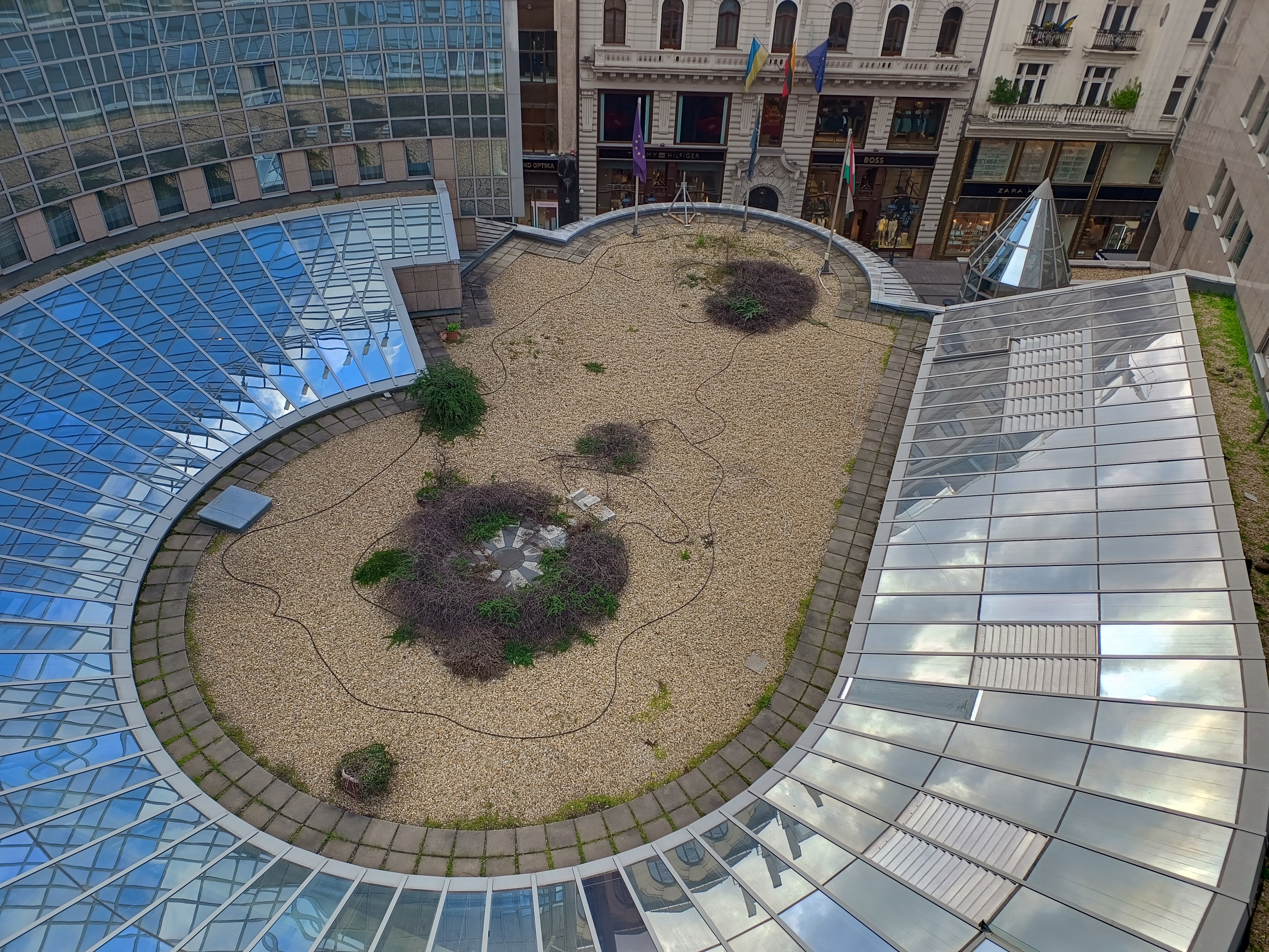 A Kempinski Hotel Corvinus impozáns, ívelt üveghomlokzata és alsó döntött üvegteteje a belső udvar felől nézve. A Nortek által szakszerűen felhelyezett kültéri hővédő ablakfólia elegáns megjelenést és maximális védelmet nyújt a nyári hőség ellen.