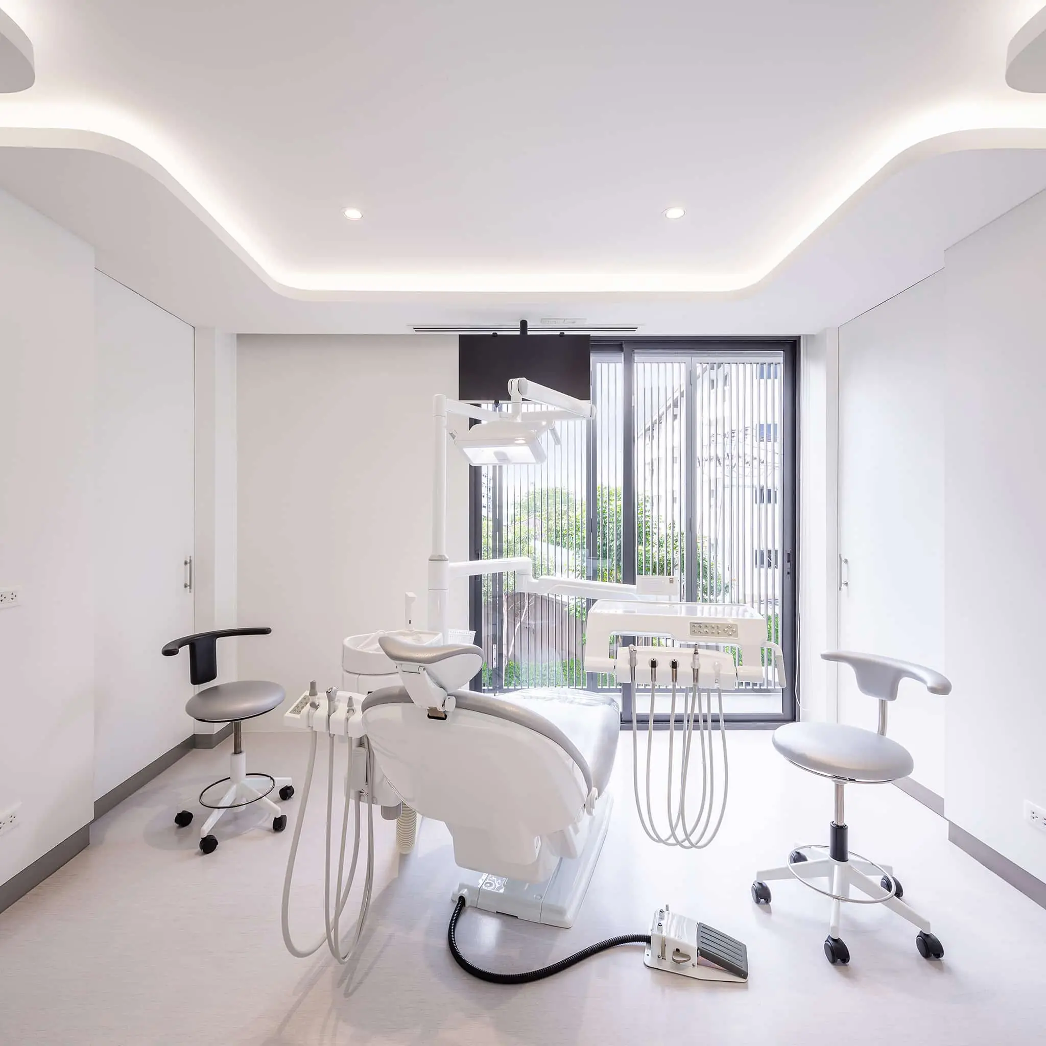 Treatment room with two dental chairs beside a window at COSDENT Rama 9
