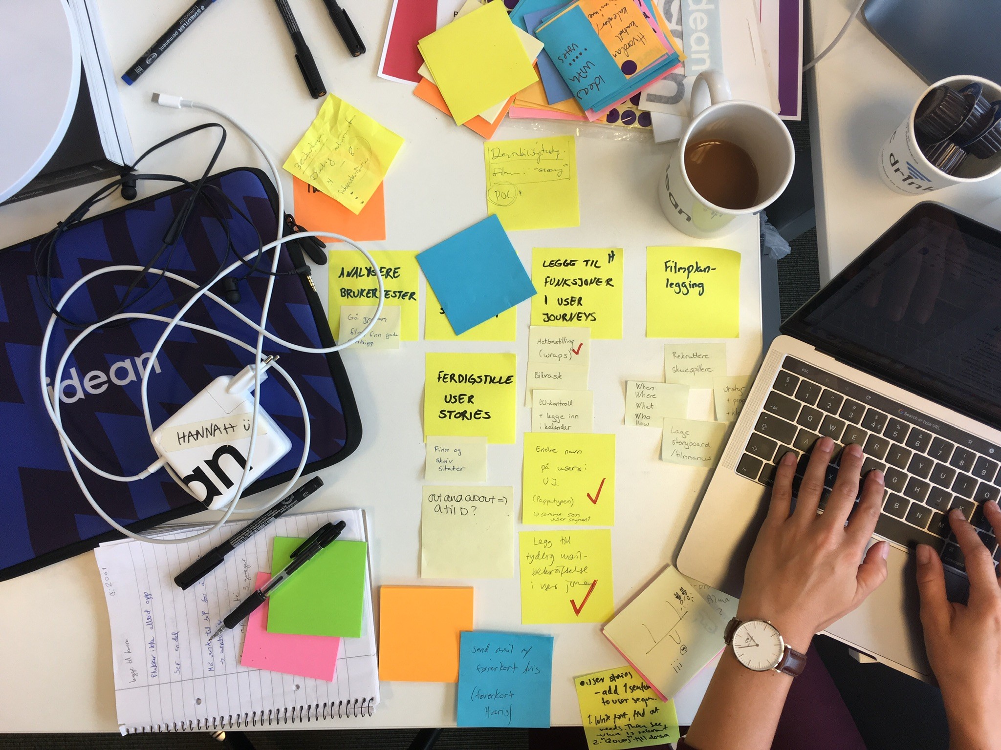 A collaborative workspace with sticky notes, laptops and workshop material spread across a desk
