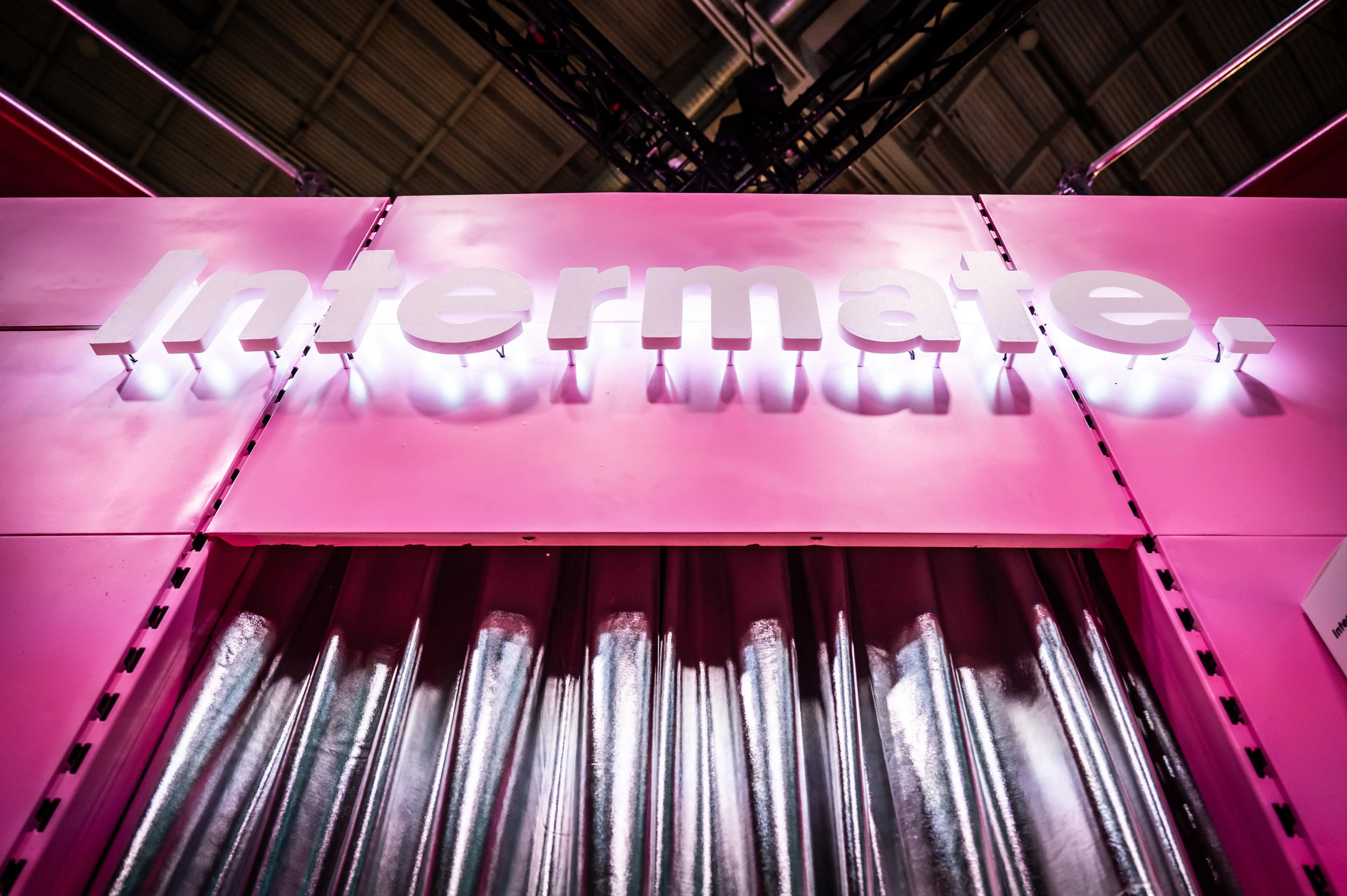 The entirely pink Intermate Social Superstore booth at OMR with scaffold walls, neon sign and central counter.