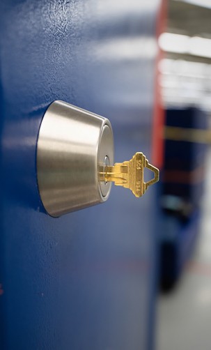 commercial lock mounted on a blue door with a key inside