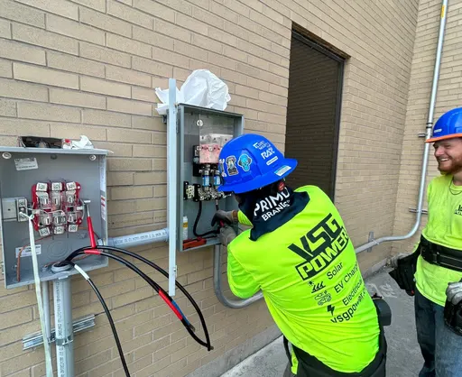 VSG Power technician working on an exterior electrical service panel on a brick building.