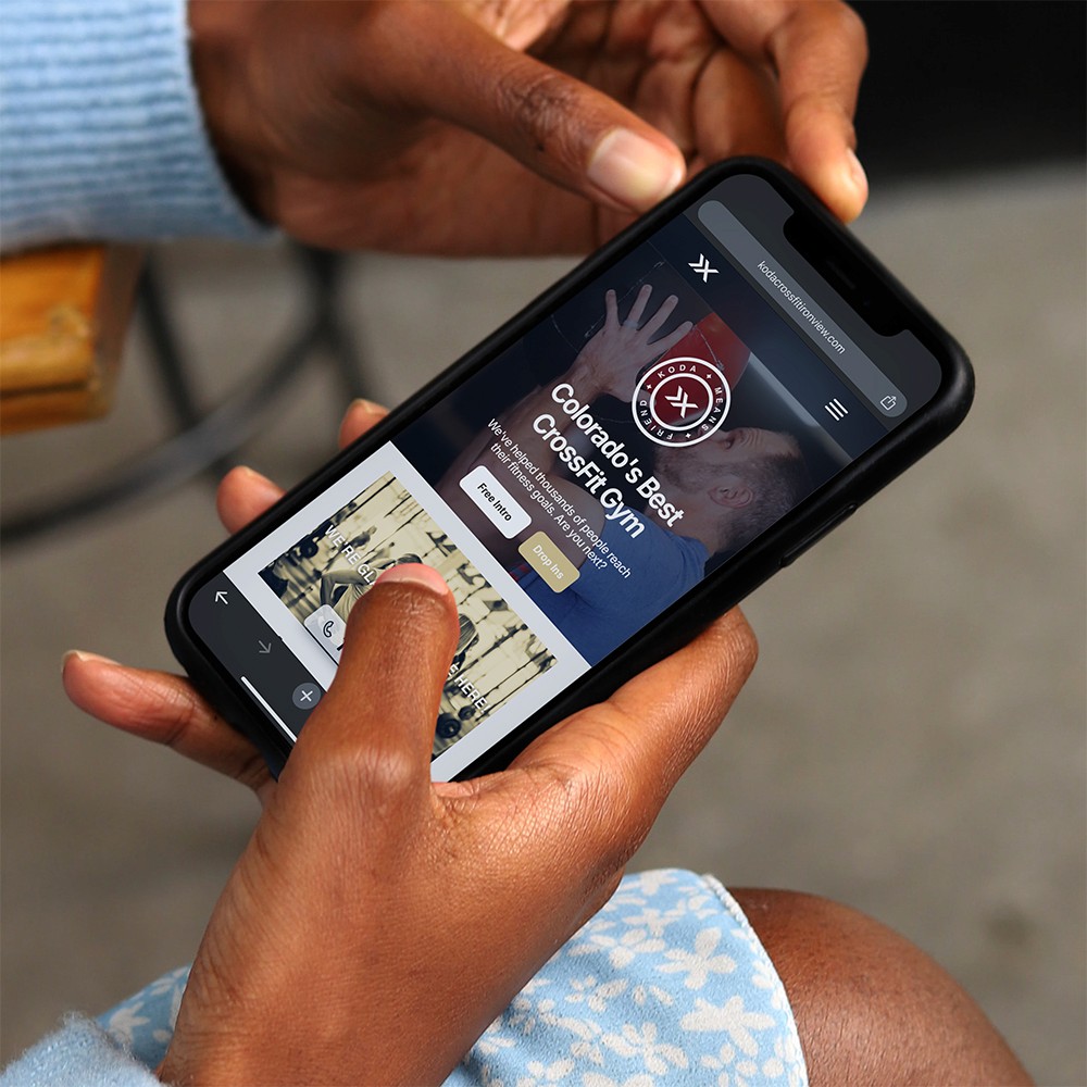 A person holding a smartphone and navigating a CrossFit gym’s website, showcasing modern mobile-friendly web design.