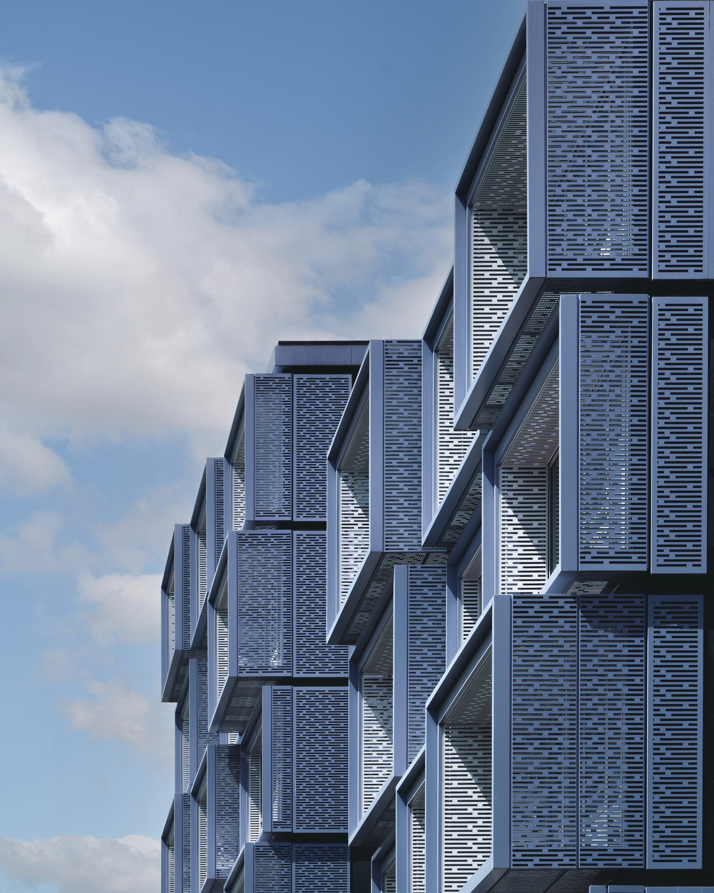 Cluster of geometric modern building facades with a cloudy sky.