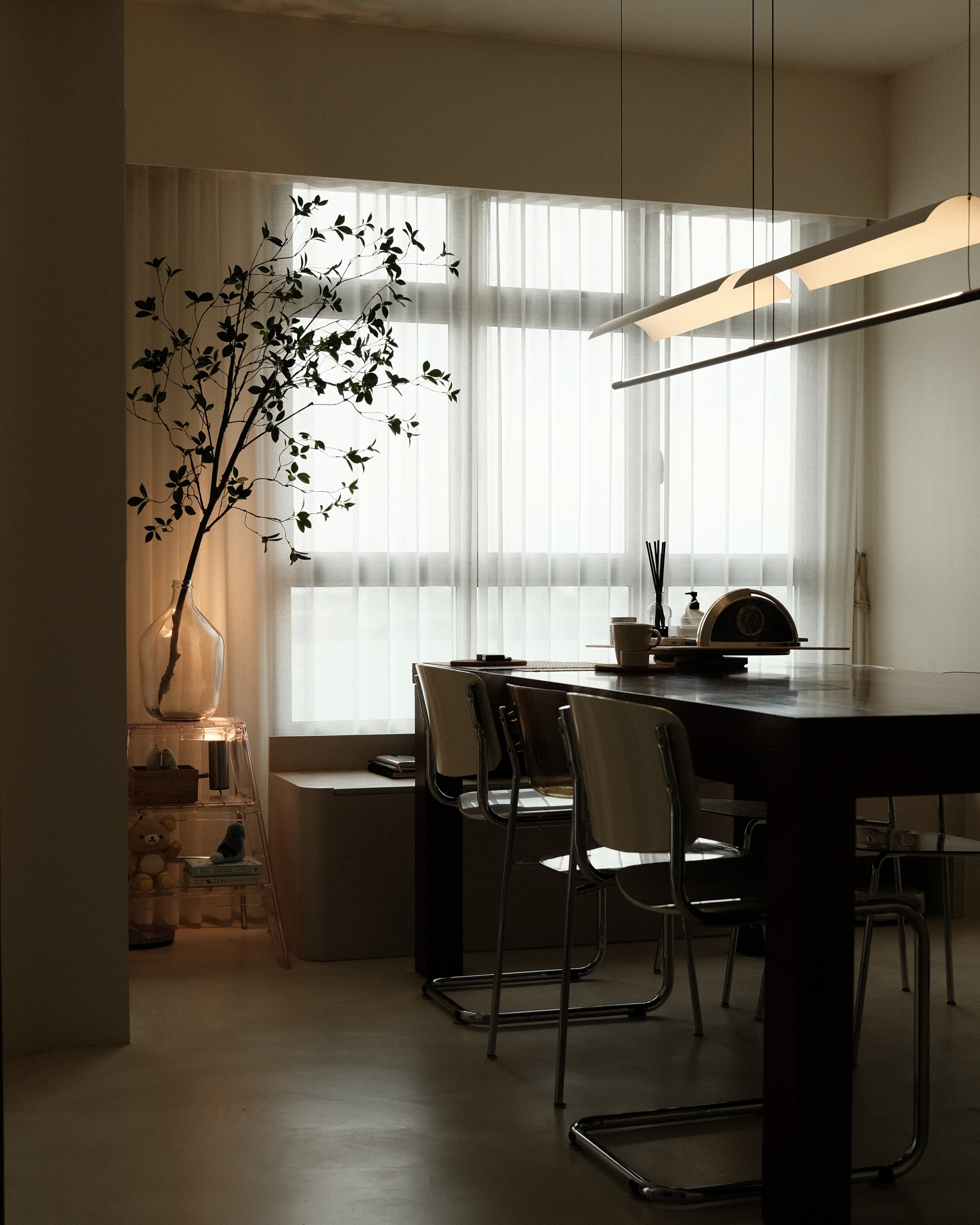 Minimalist dining area with sheer curtains, custom pendant light, and greenery (Scandinavian-inspired renovation, Singapore)