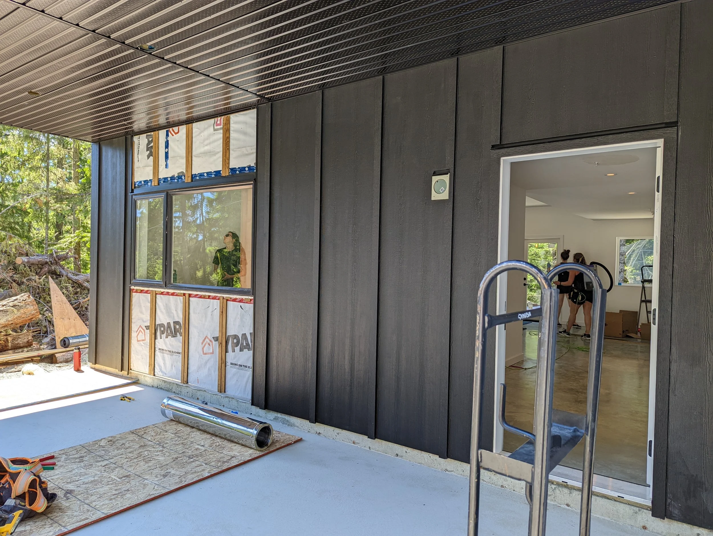 Modern two-story home with large glass windows, warmly lit interiors, and a balcony. Surrounded by trees and a manicured lawn at dusk. Cozy ambiance.