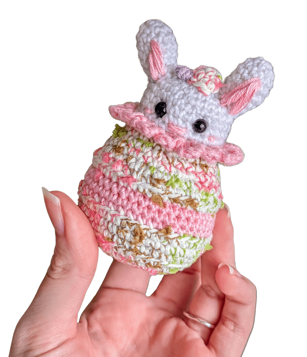 A cute, handcrafted plush acorn toy with brown yarn spikes and large, friendly eyes sits facing forward on a white background.