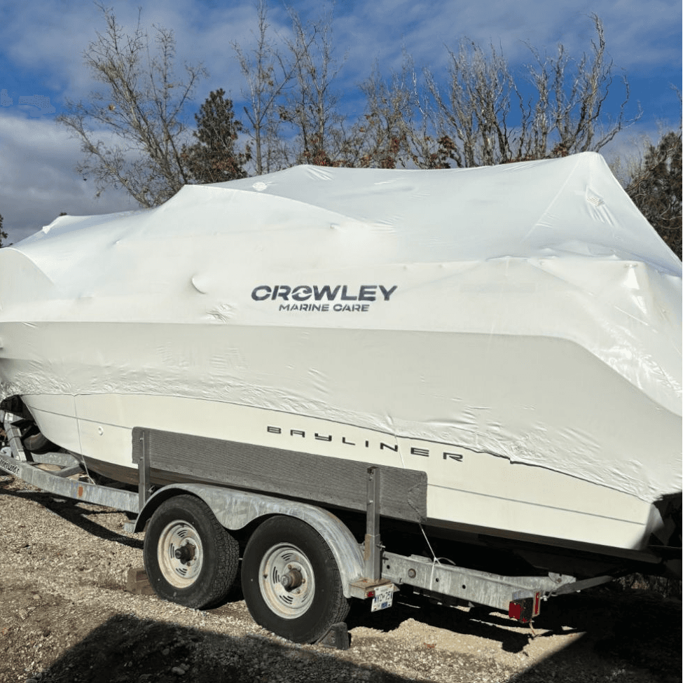 A boat that has been shrink wrapped and protected for winter with Crowley Marine Care branding