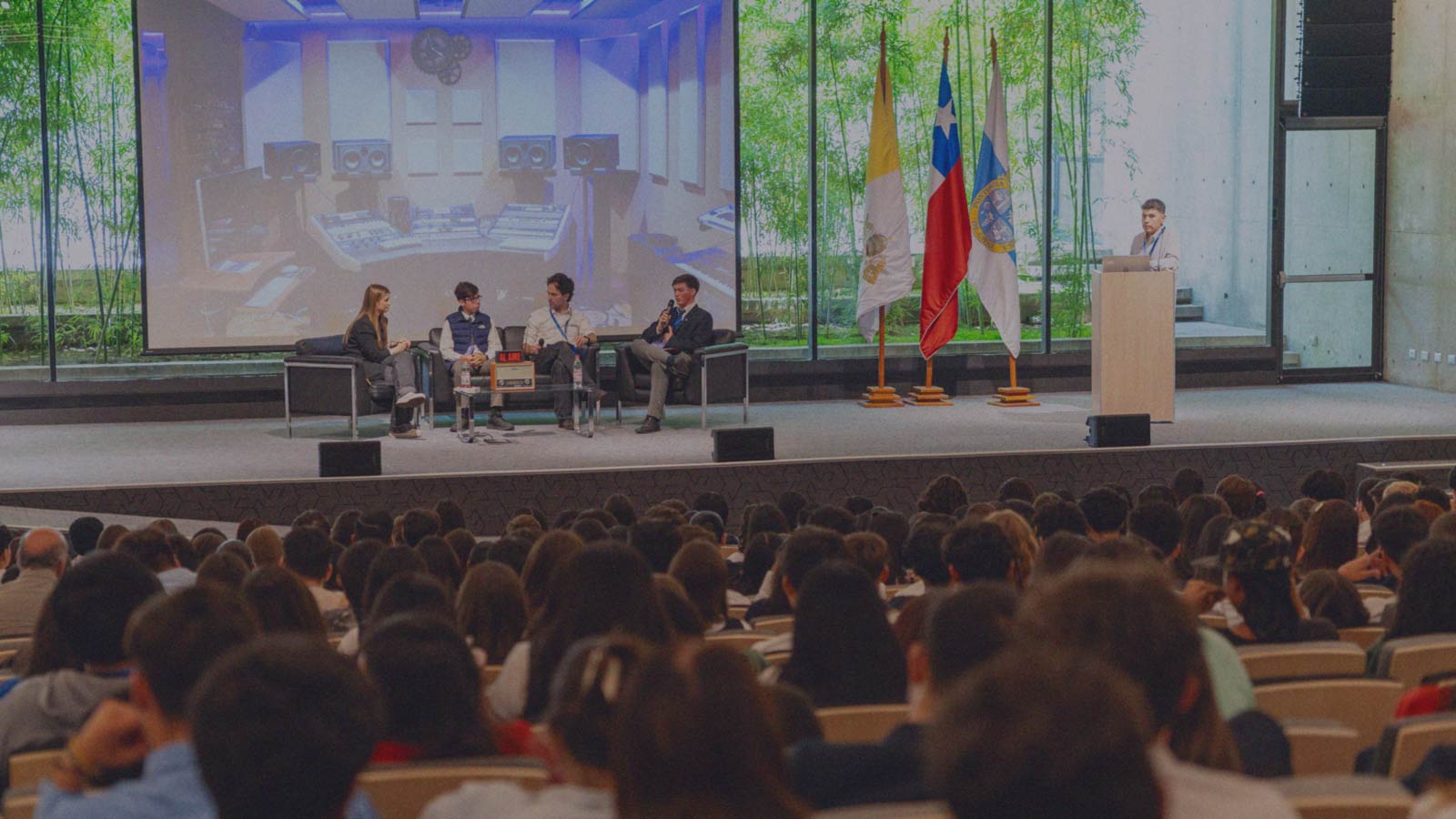 Portada de ELIJO, programa de formación de IdeaPaís, mostrando un auditorio en que cientos de escolares escuchan a expositores que hay sobre un escenario o tarima. 
