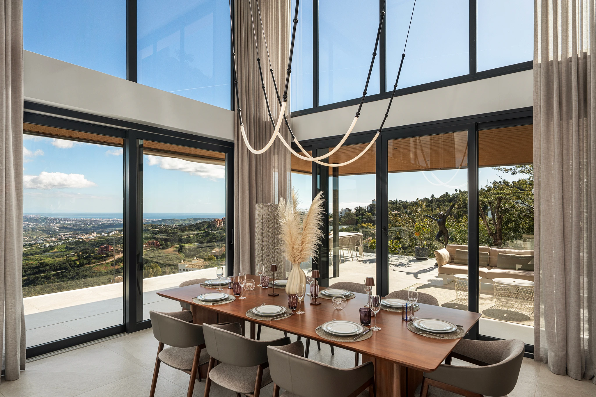 Villa Vista Marbella dining area with panoramic glazing, set wooden table, and hillside views