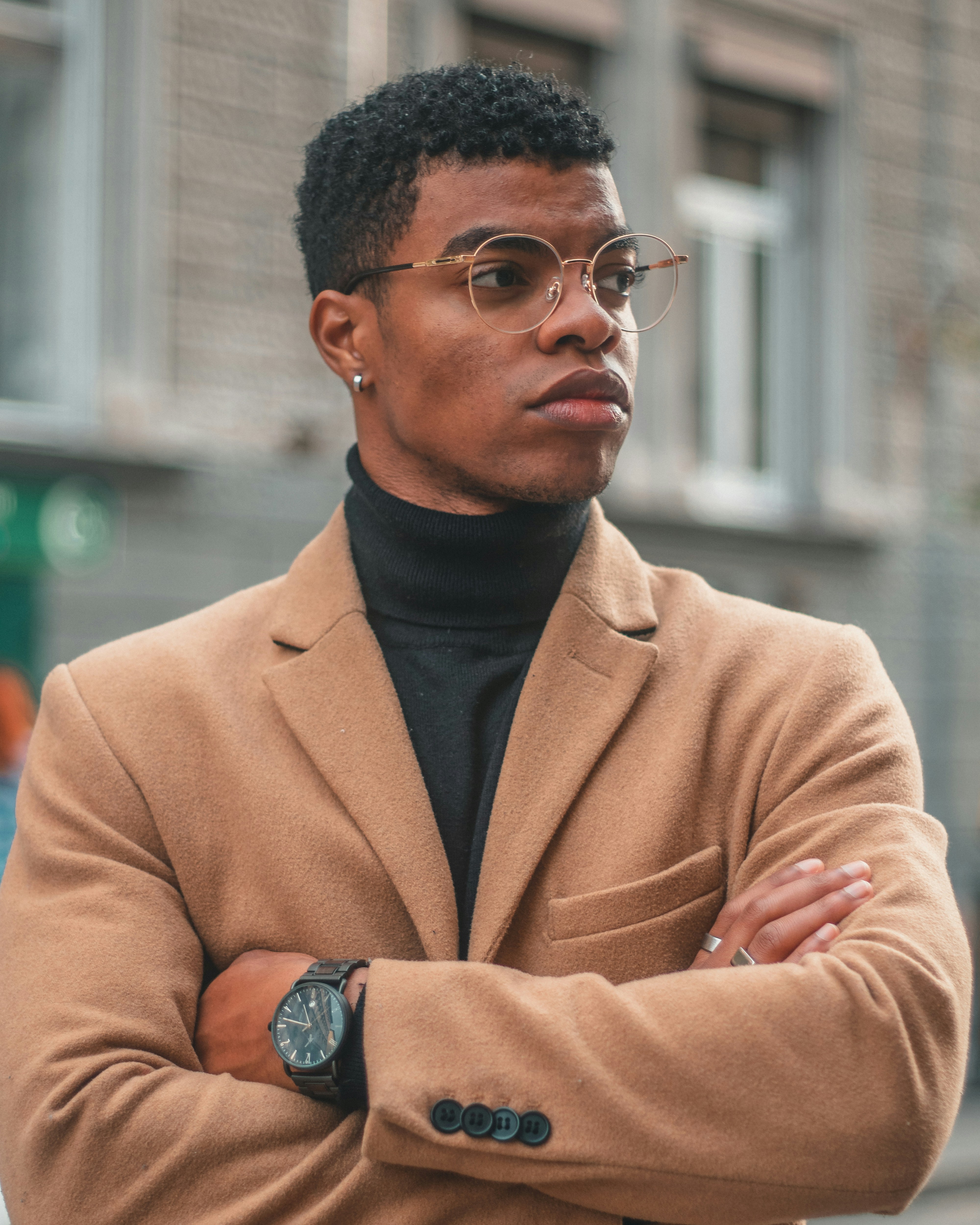 A man in stylish attire looks thoughtfully.