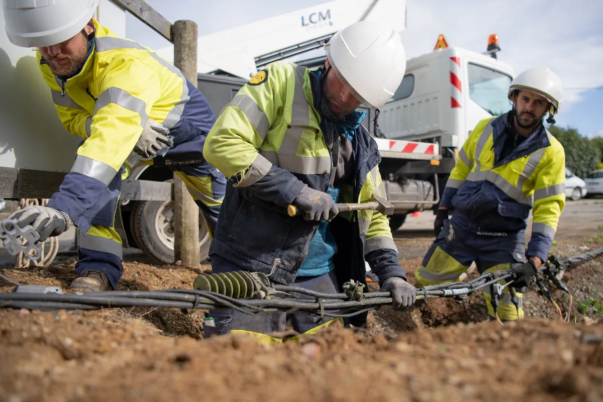 Équipe de techniciens réseaux en gilets jaunes travaillant sur câblage enterré extérieur