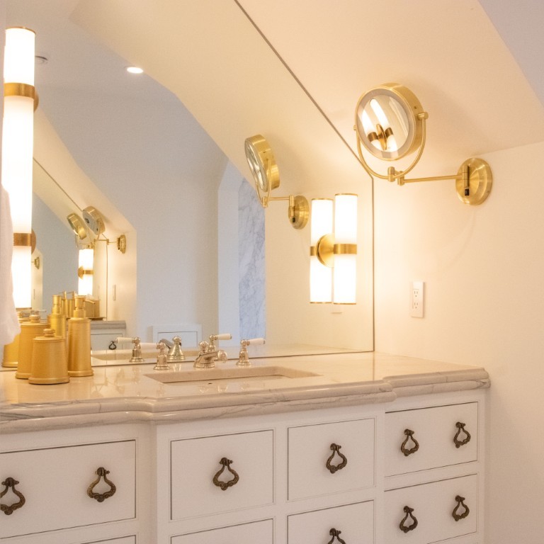 Image of Luxurious bathroom vanity with marble countertop, gold fixtures, and elegant lighting by KHD Homes designers.