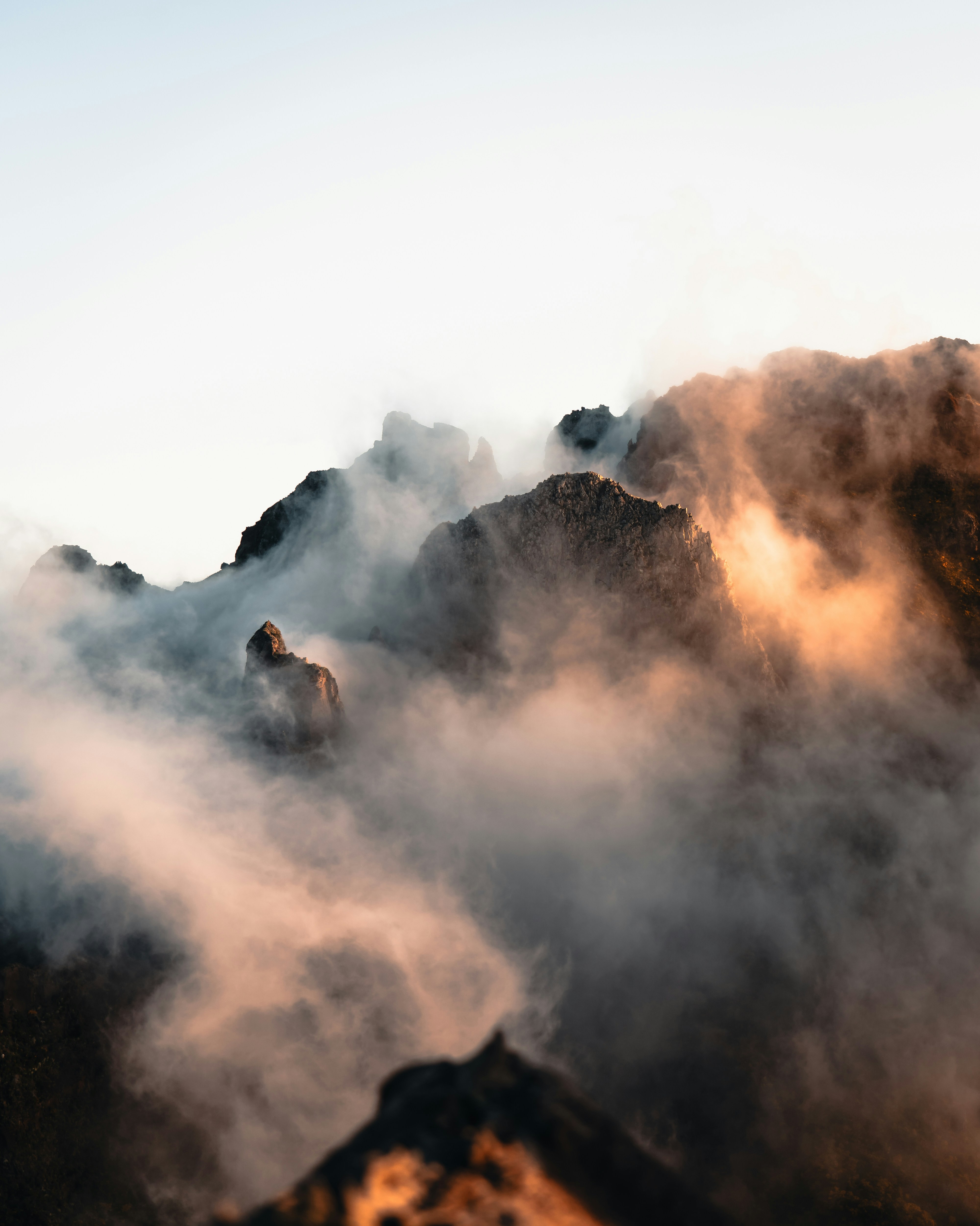 Misty mountain peaks at sunrise with warm light.