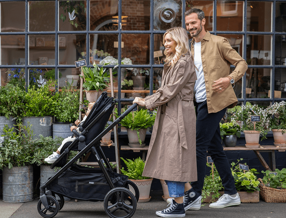 A young couple walking with their baby in a buggy