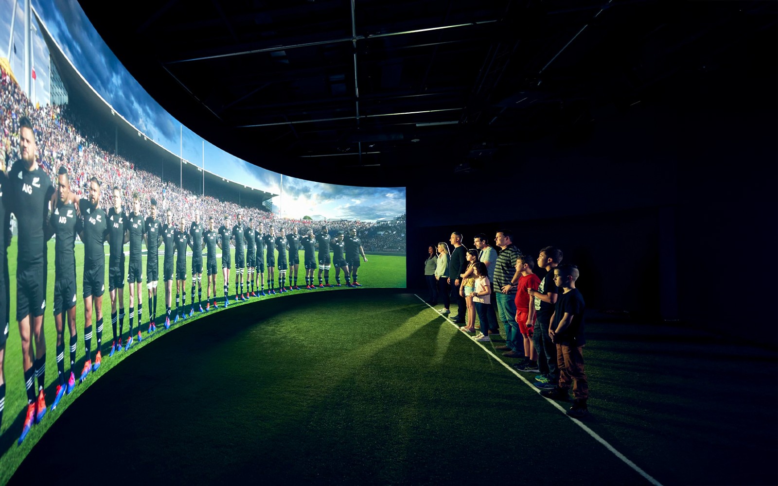 Visitors watching All Blacks rugby team video at New Zealand experience exhibit.