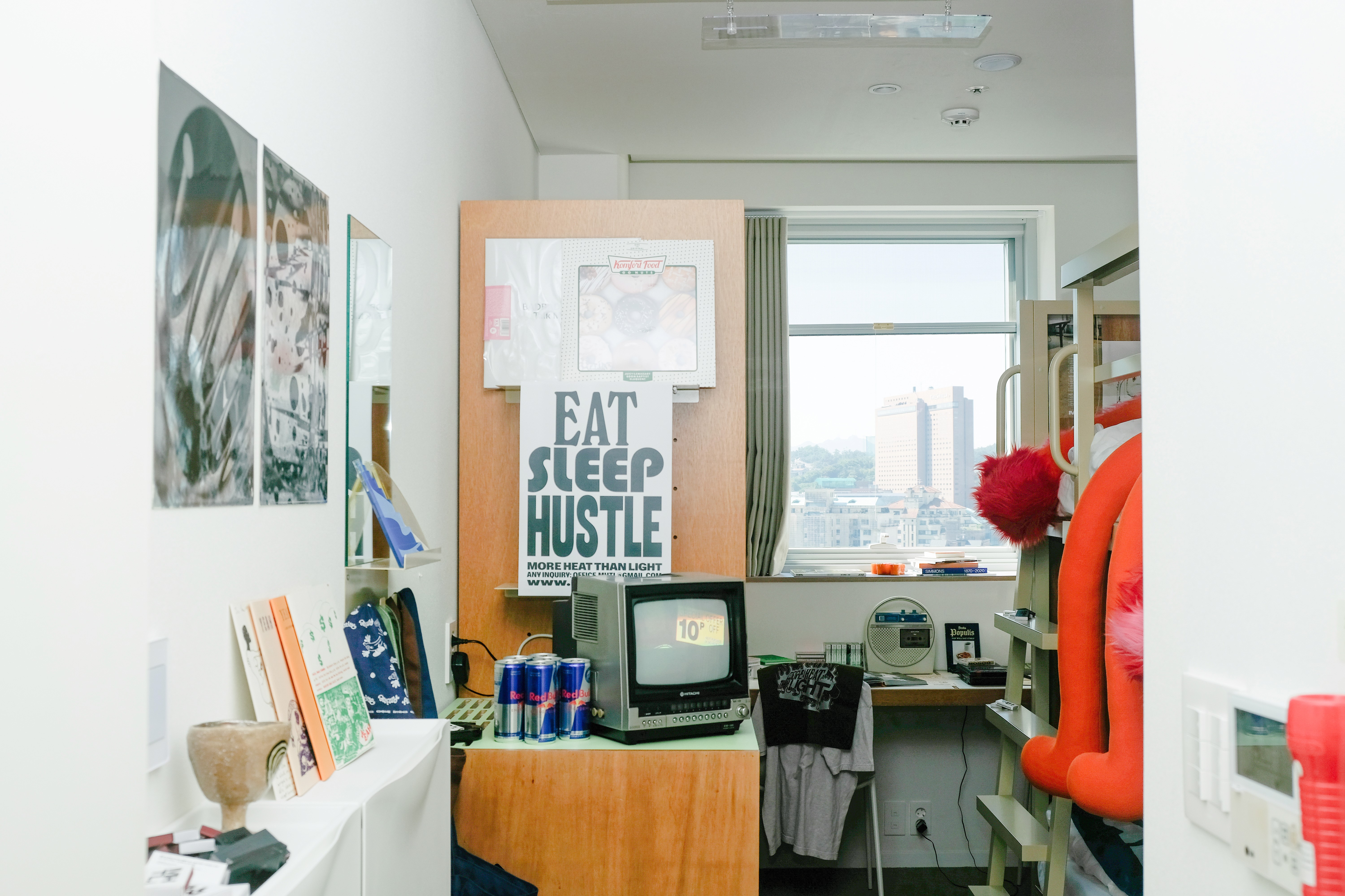 A woman with her hair tied back smiles while reading an open book in the library at Mangrove Sinchon.