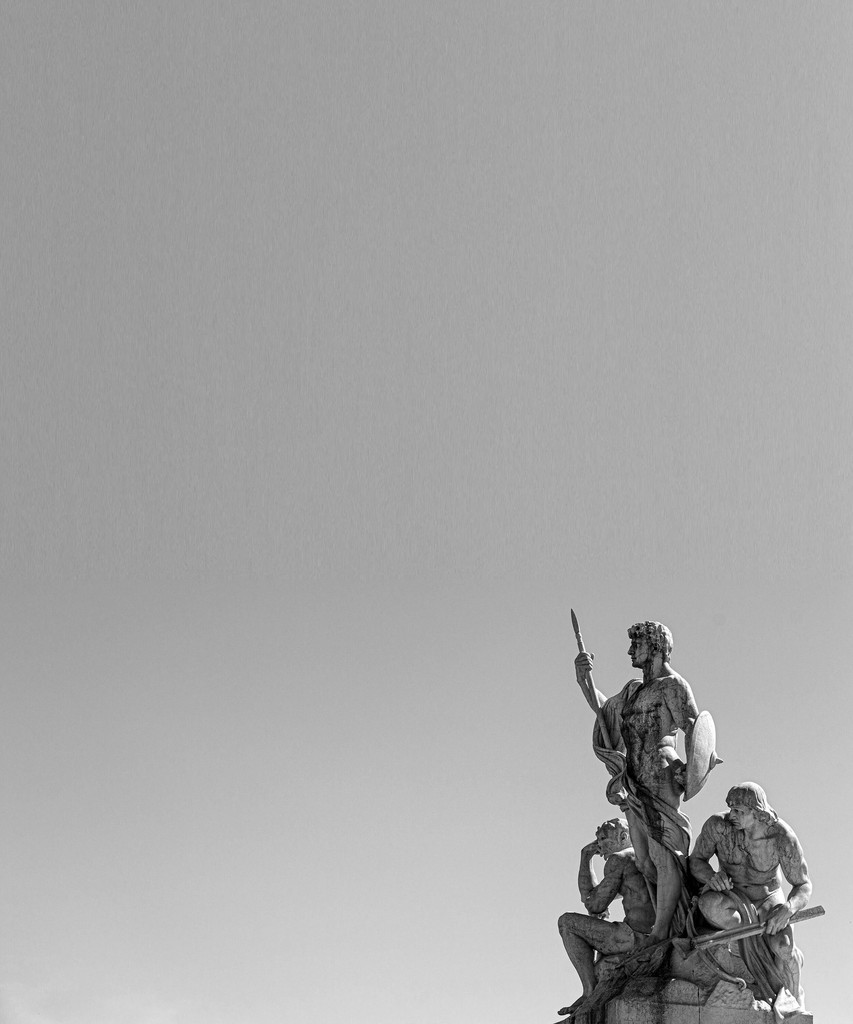 Statues on a monument silhouetted against a grey sky