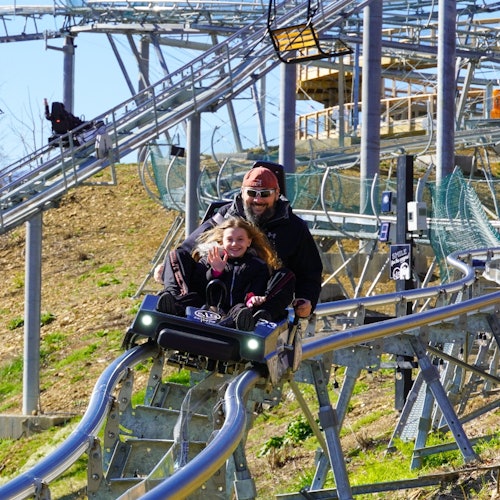 બીજાં લોકો ખુશીની સાથે હસતા અને મેટલ ટ્રેક પર વ્યક્તિગત રોલર કોસ્ટર ચલાવતા થતી વખતે હાથ હલાવવાનું.