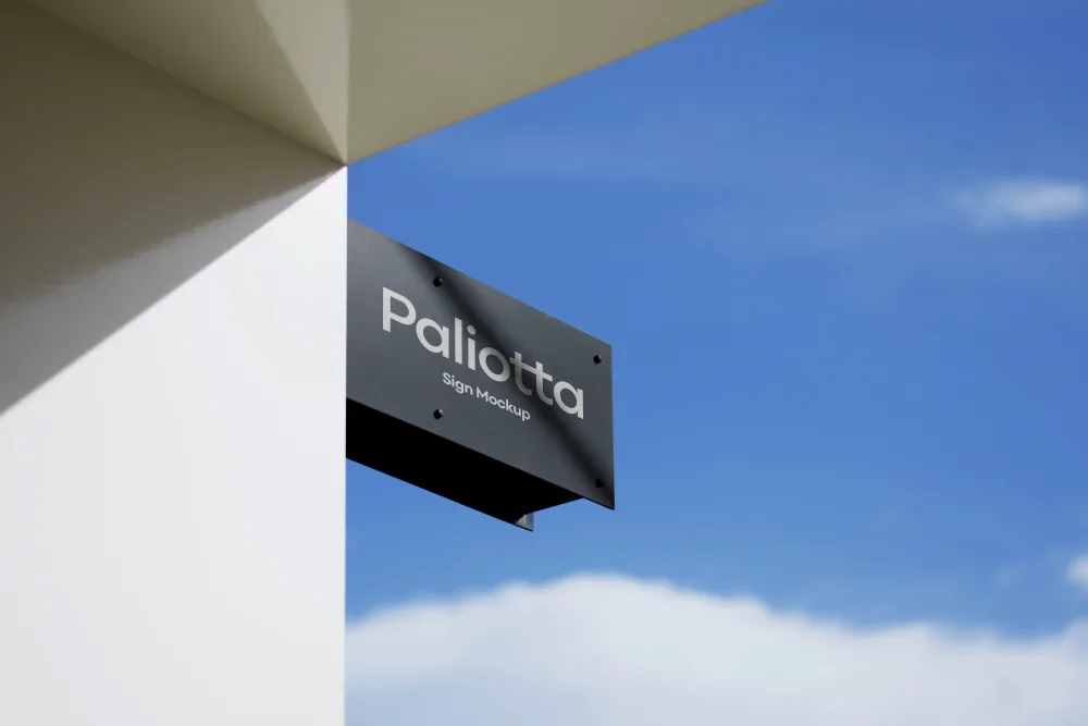 Modern rectangular outdoor signage mounted on a white building corner, featuring repeated branding on a dark blue background. Bright blue sky with soft clouds in the background.