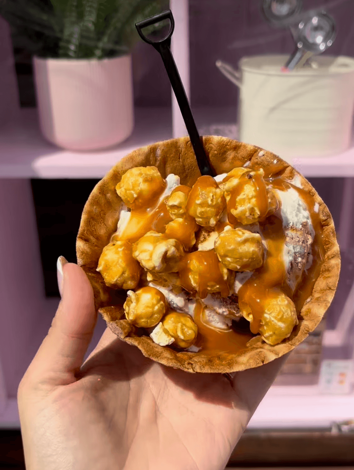Waffle bowl filled with salted caramel ice cream, topped with caramel drizzle and caramel popcorn