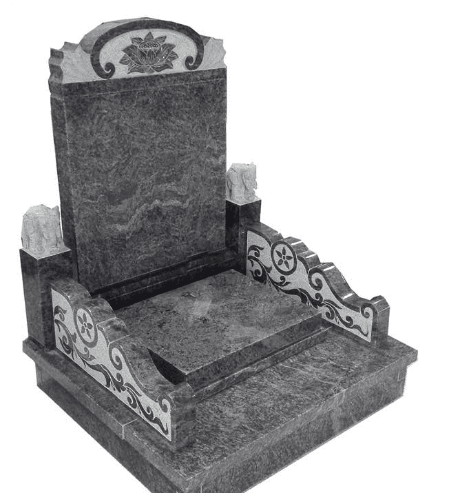 An elaborately designed grey granite tombstone with decorative side panels featuring traditional motifs. The tombstone includes a highly detailed top carving, making it a prominent memorial piece.